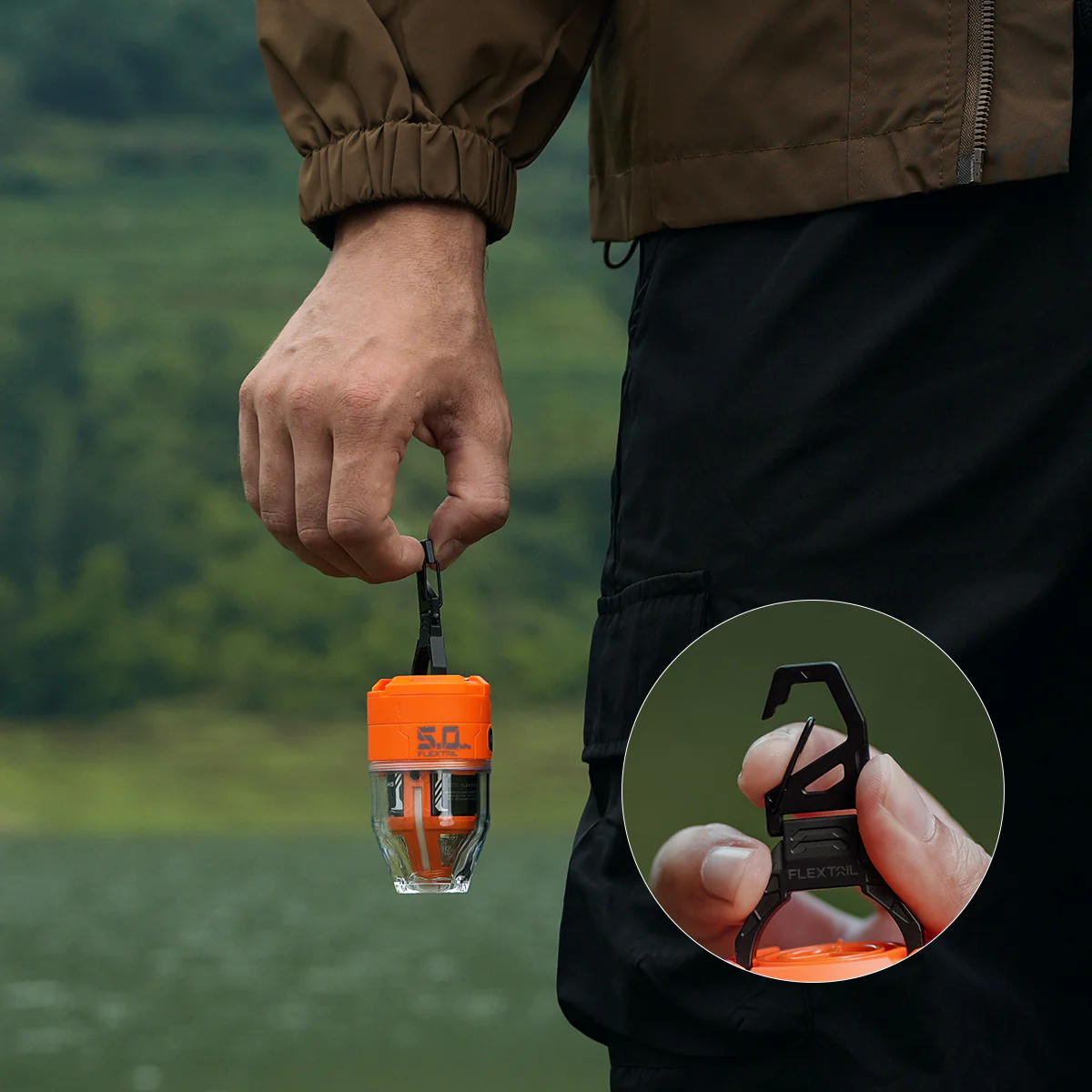 Egy személy egy narancssárga és átlátszó eszközt tart, fekete klipszel. A háttérben egy tó és zöld dombok láthatók.