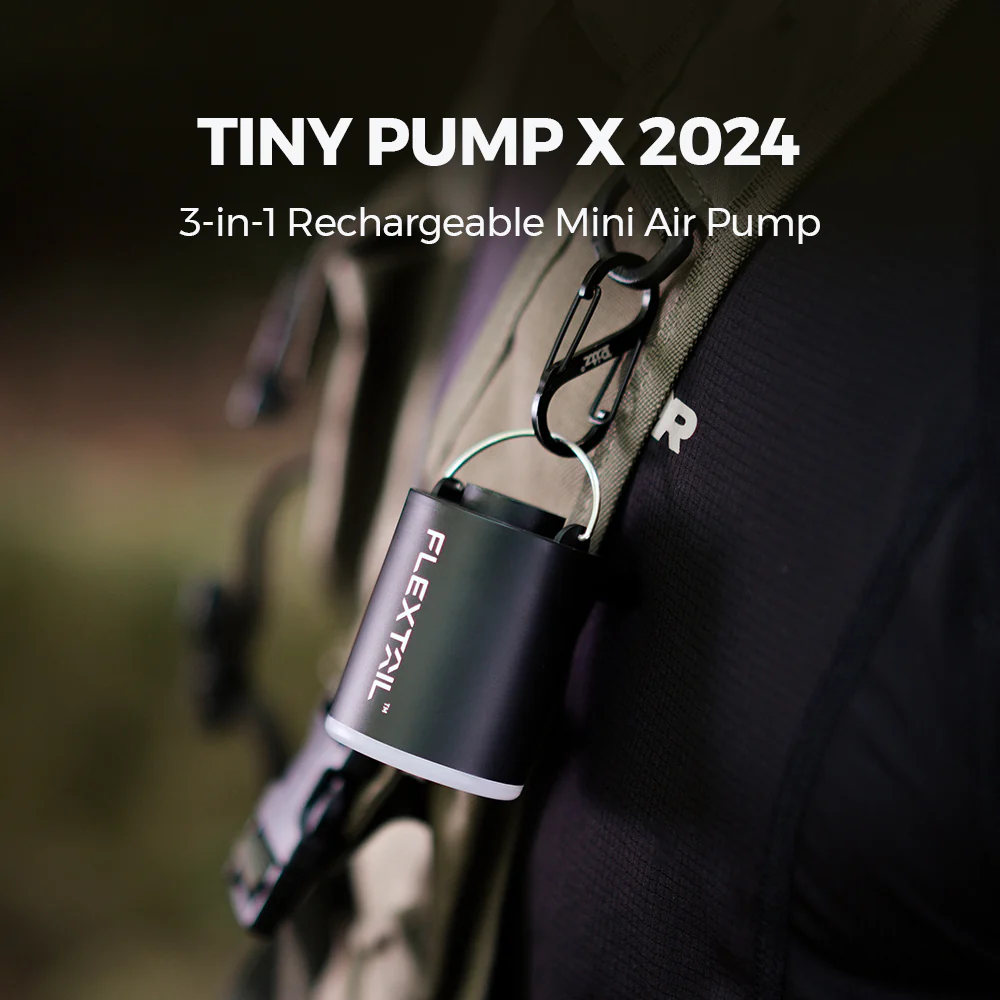 Egy fekete Tiny Pump X 2024 egy hátizsákpánthoz van rögzítve. A szivattyú hengeres, fehér fénnyel. A szöveg: 'FLEXTAIL'.