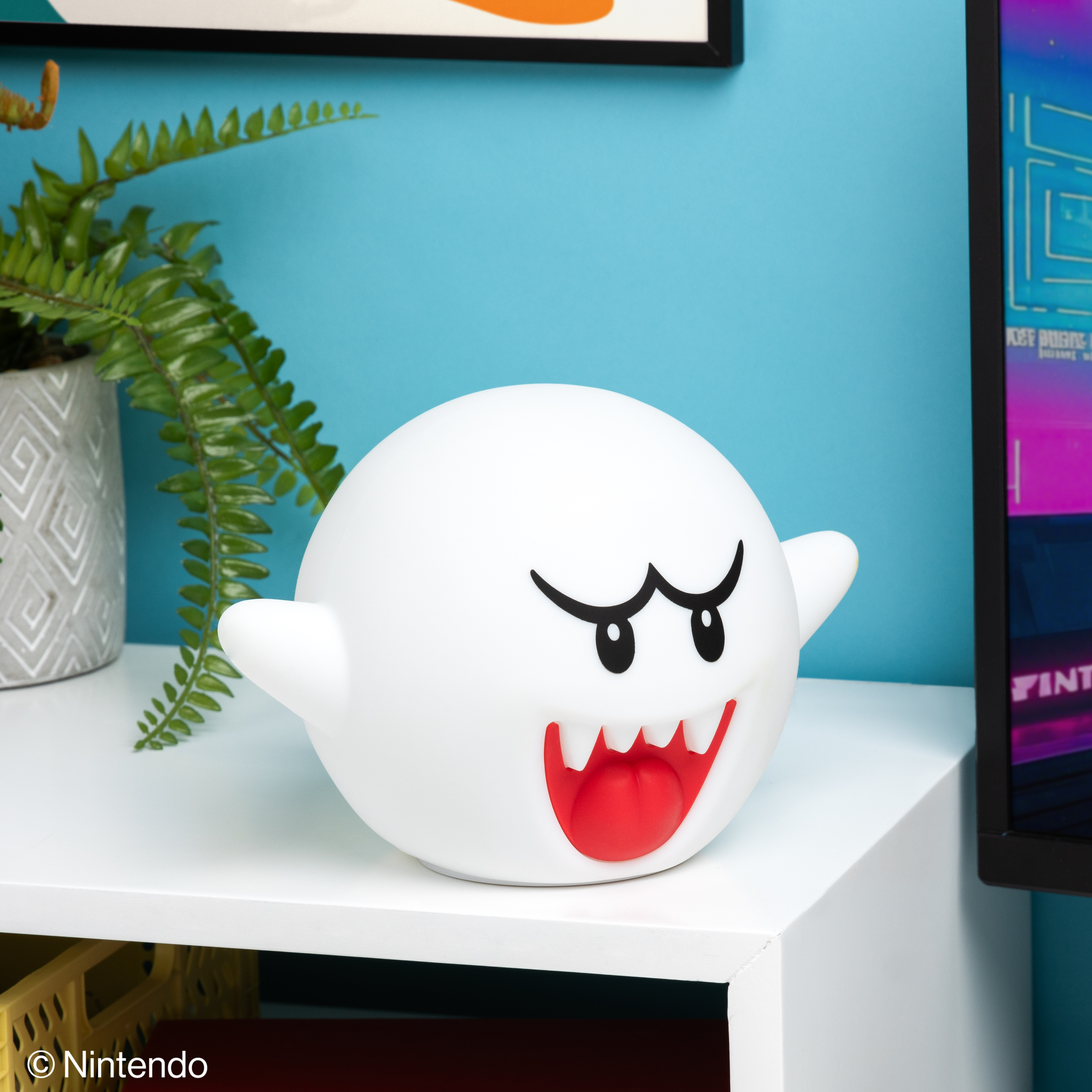 Weiße Boo-Lampe auf einem weißen Schreibtisch. Farn links. Blauer Wandhintergrund, rechts ein Computermonitor.