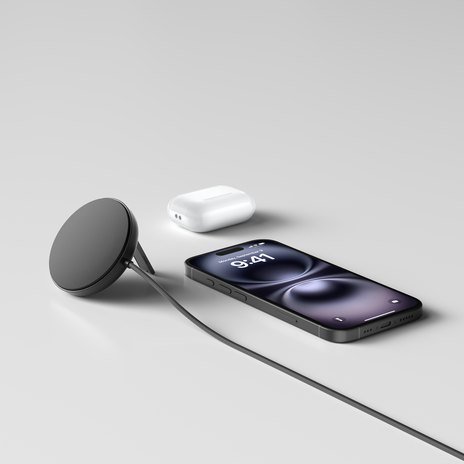 Un iPhone, des AirPods et un chargeur sans fil noir sont sur une surface blanche. Le téléphone affiche l'heure.