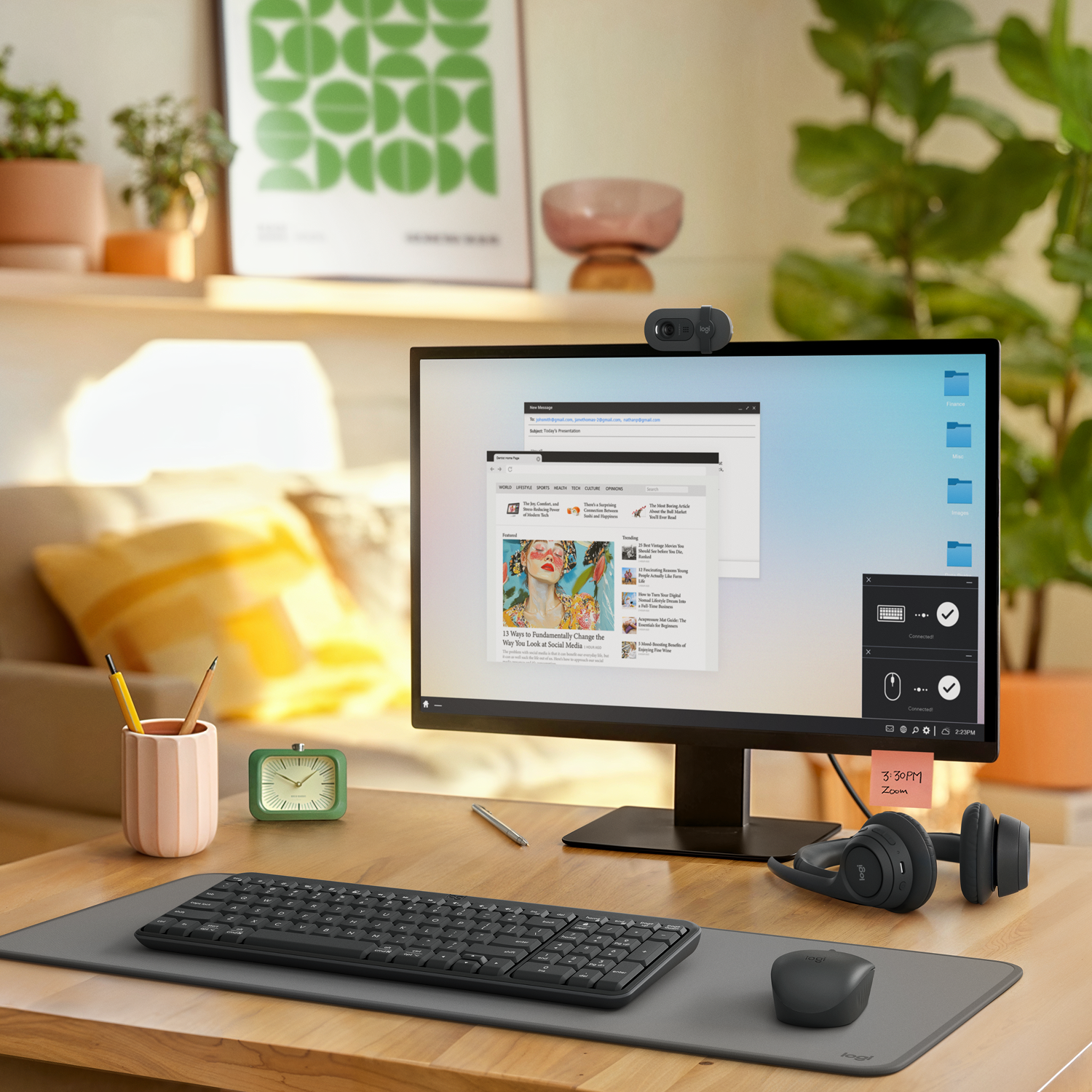 Una configuración de escritorio con monitor, teclado, ratón y auriculares. Una webcam está encima del monitor. Un reloj y un bolígrafo están en el escritorio.