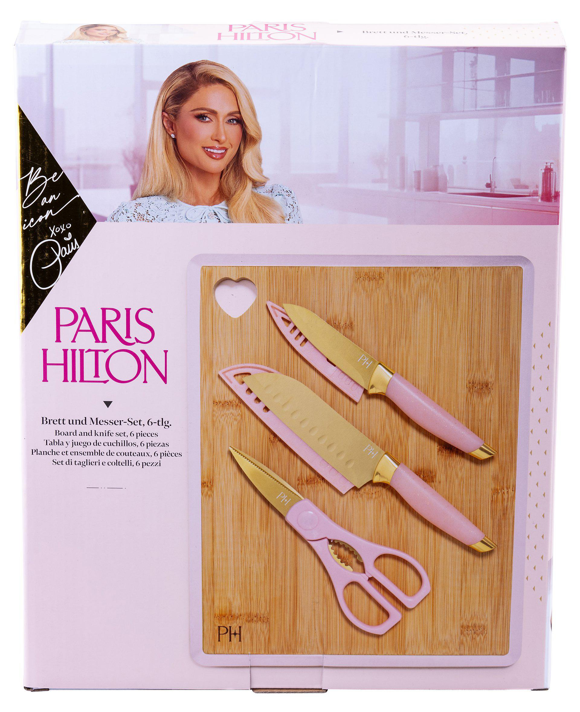 Ein Messer-Set der Marke Paris Hilton wird gezeigt. Es enthält ein Schneidebrett und Messer und Scheren mit rosa Griffen.