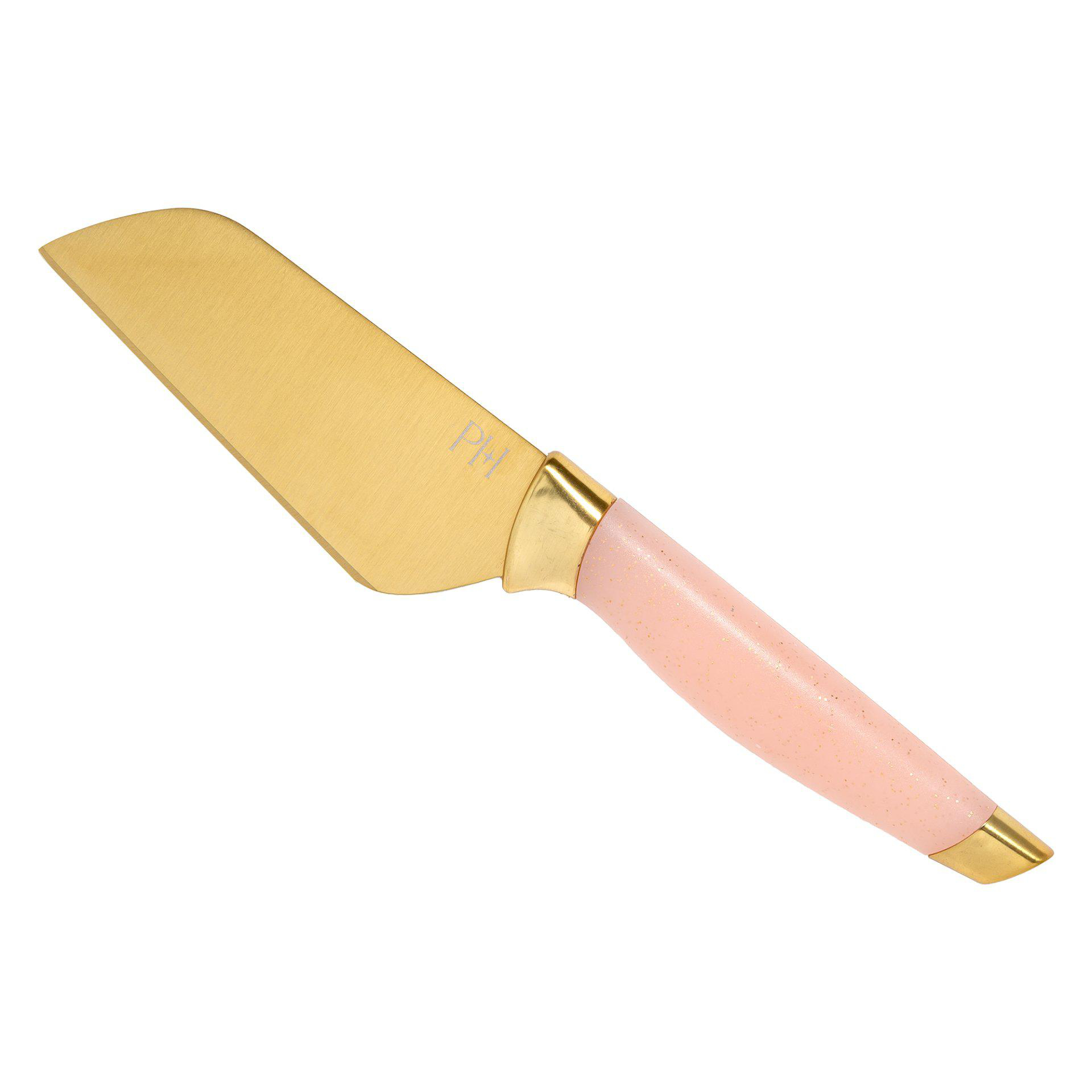 Ein goldenes Käsemesser mit rosa Griff. Es hat eine breite, flache Klinge und eine leicht gebogene Kante.