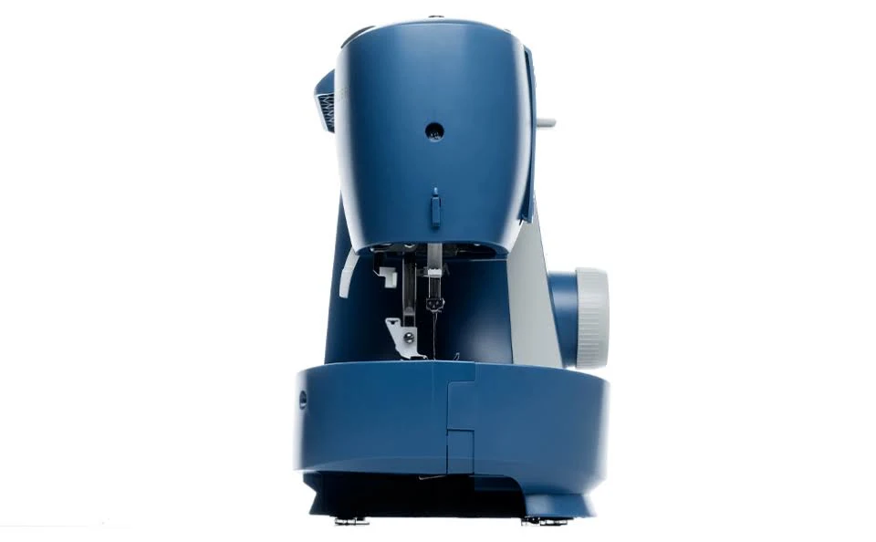 Una máquina de coser azul, vista de lado, sobre un fondo blanco. Tiene una aguja, una rueda grande y varios controles.