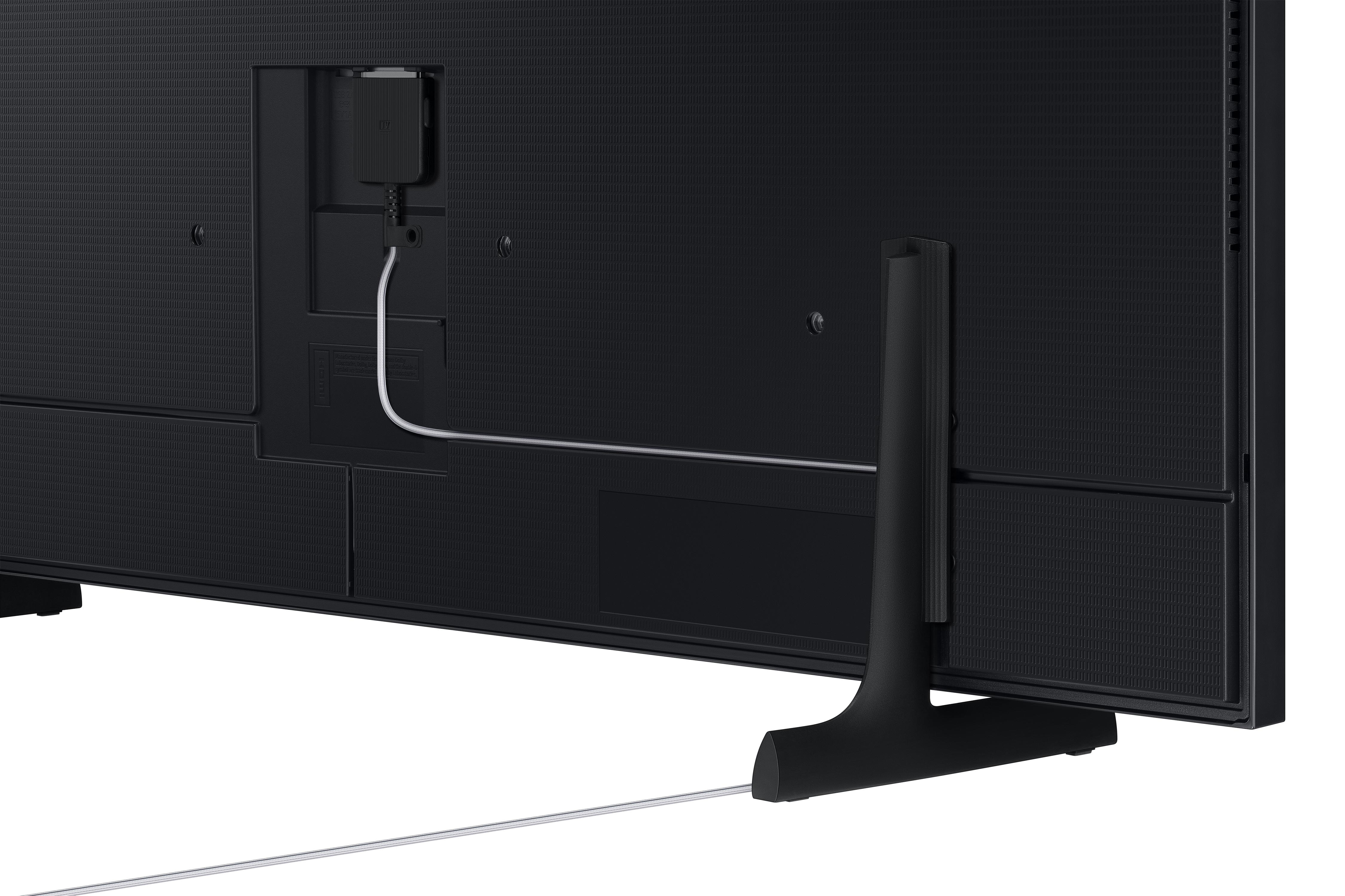 Schwarze TV-Rückseite mit Anschlüssen und weißem Kabel. Ein Ständer hält den Fernseher. Strukturierte Oberfläche und Stecker.