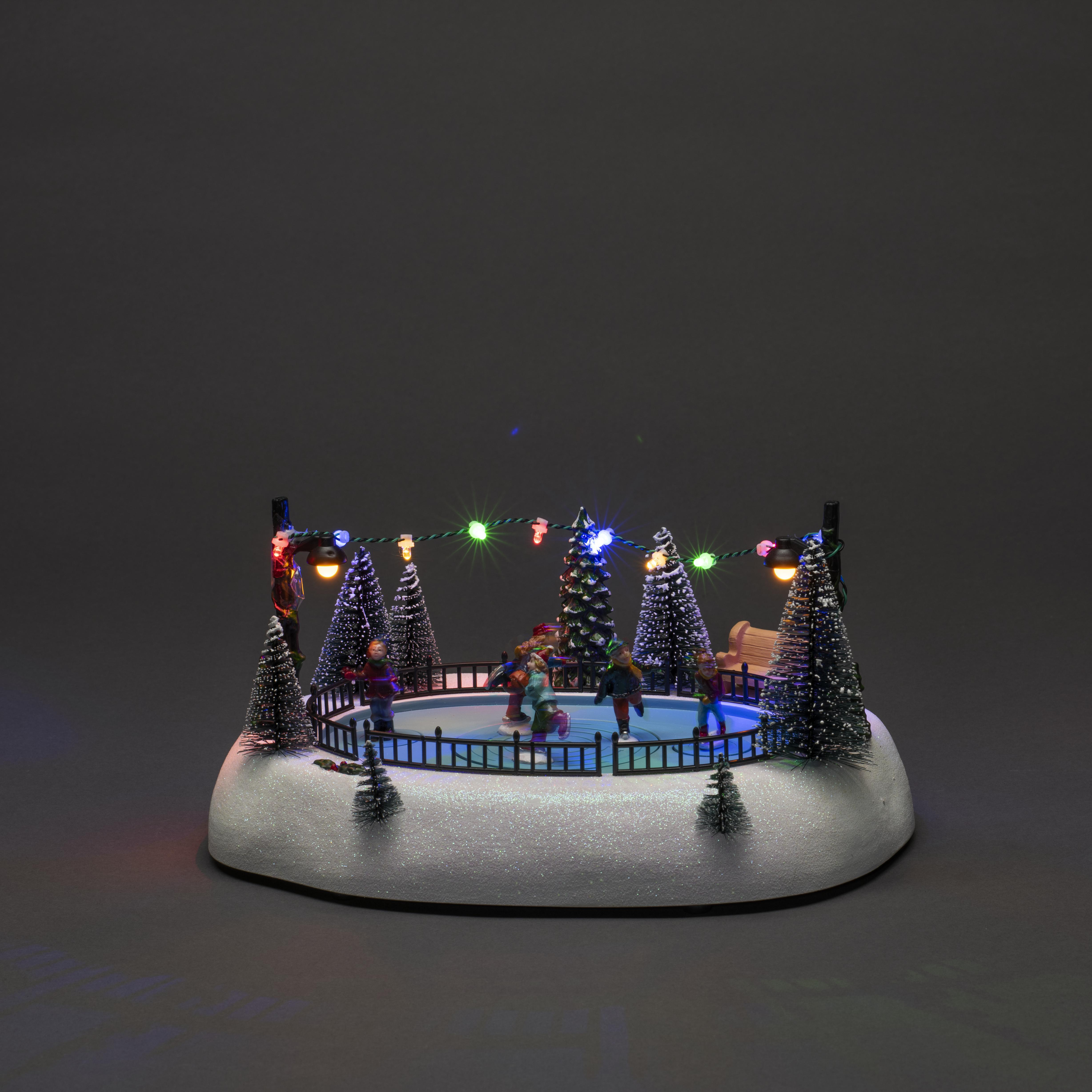 Miniatur-Eislaufszene mit Figuren, Bäumen und Lichtern. Ein dekoratives Winter-Feiertags-Diorama auf grauem Grund.