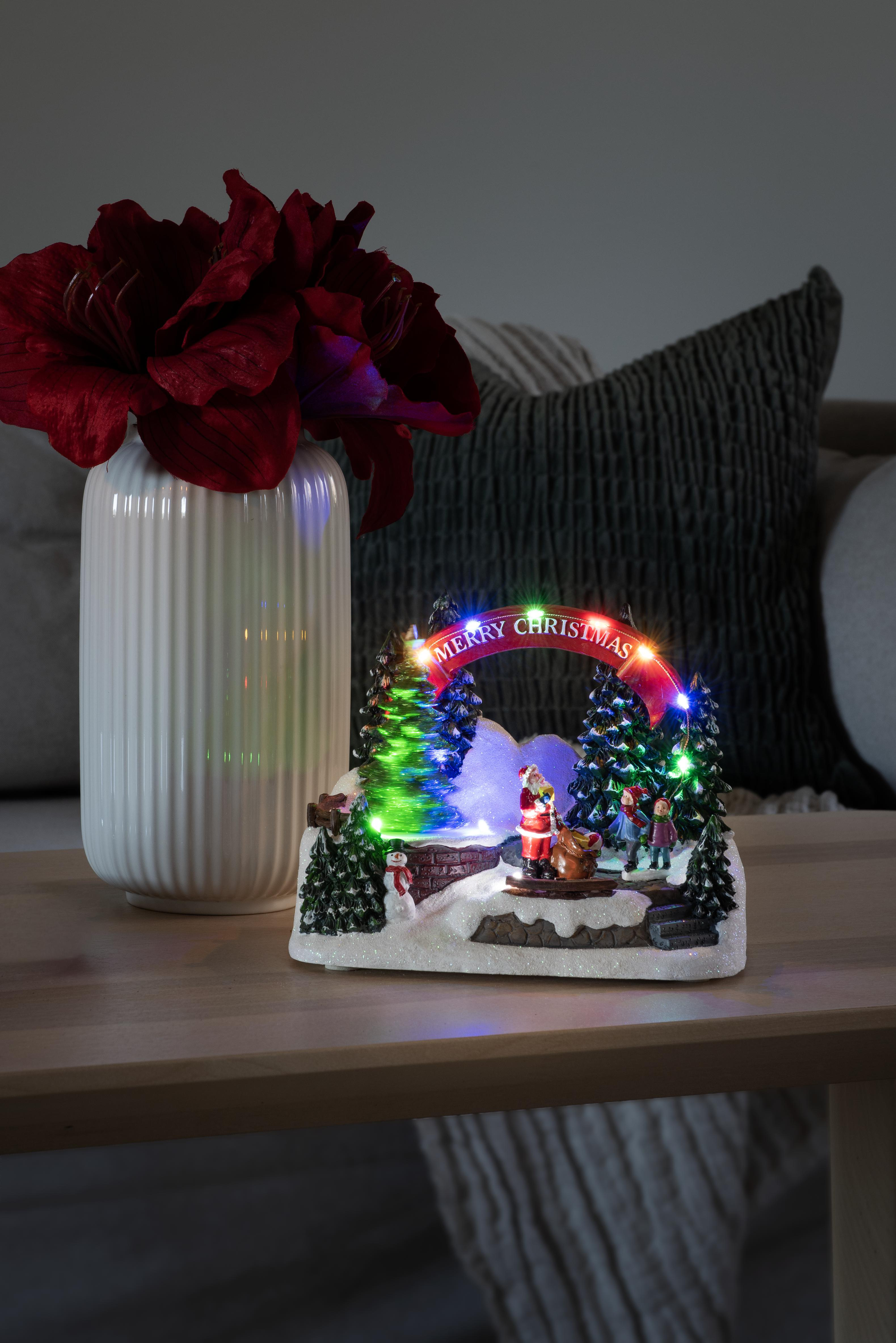 Weihnachtsszene, Weihnachtsmann und Kinder, Schnee, Bäume und ein 'Merry Christmas'-Bogen. Vase mit Blumen.