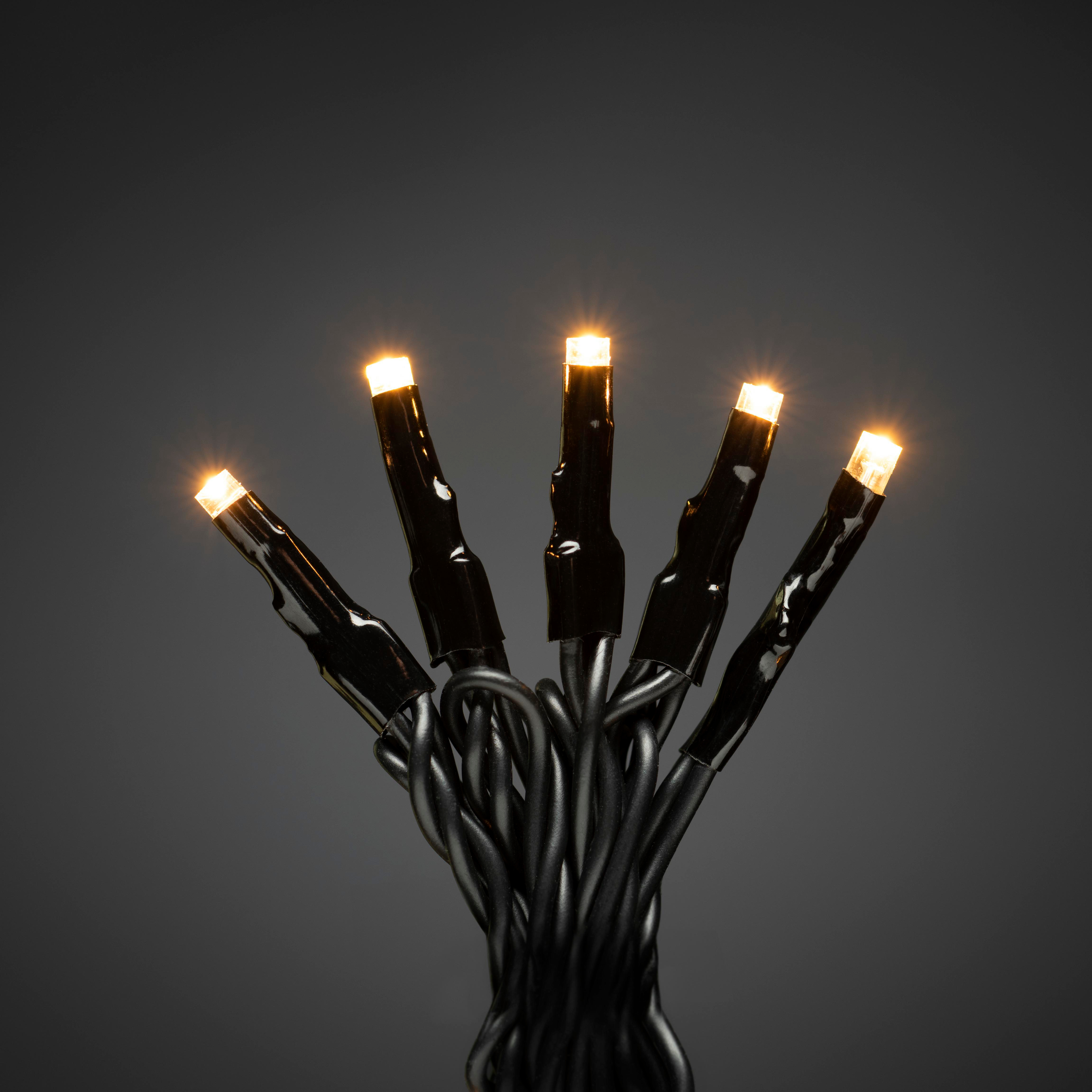 Nahaufnahme einer Lichterkette mit fünf warmweißen LEDs und schwarzen Drähten vor dunklem Hintergrund.