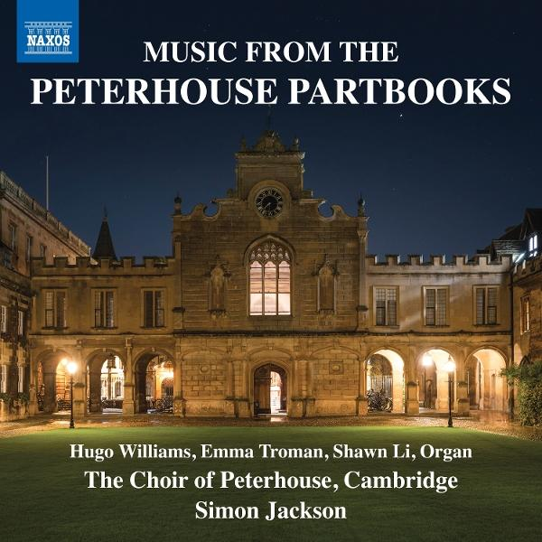 Nachtansicht des Peterhouse College, Cambridge. Das Gebäude ist beleuchtet, mit einem Uhrturm und einem gewölbten Eingang. Grünes Gras im Vordergrund.