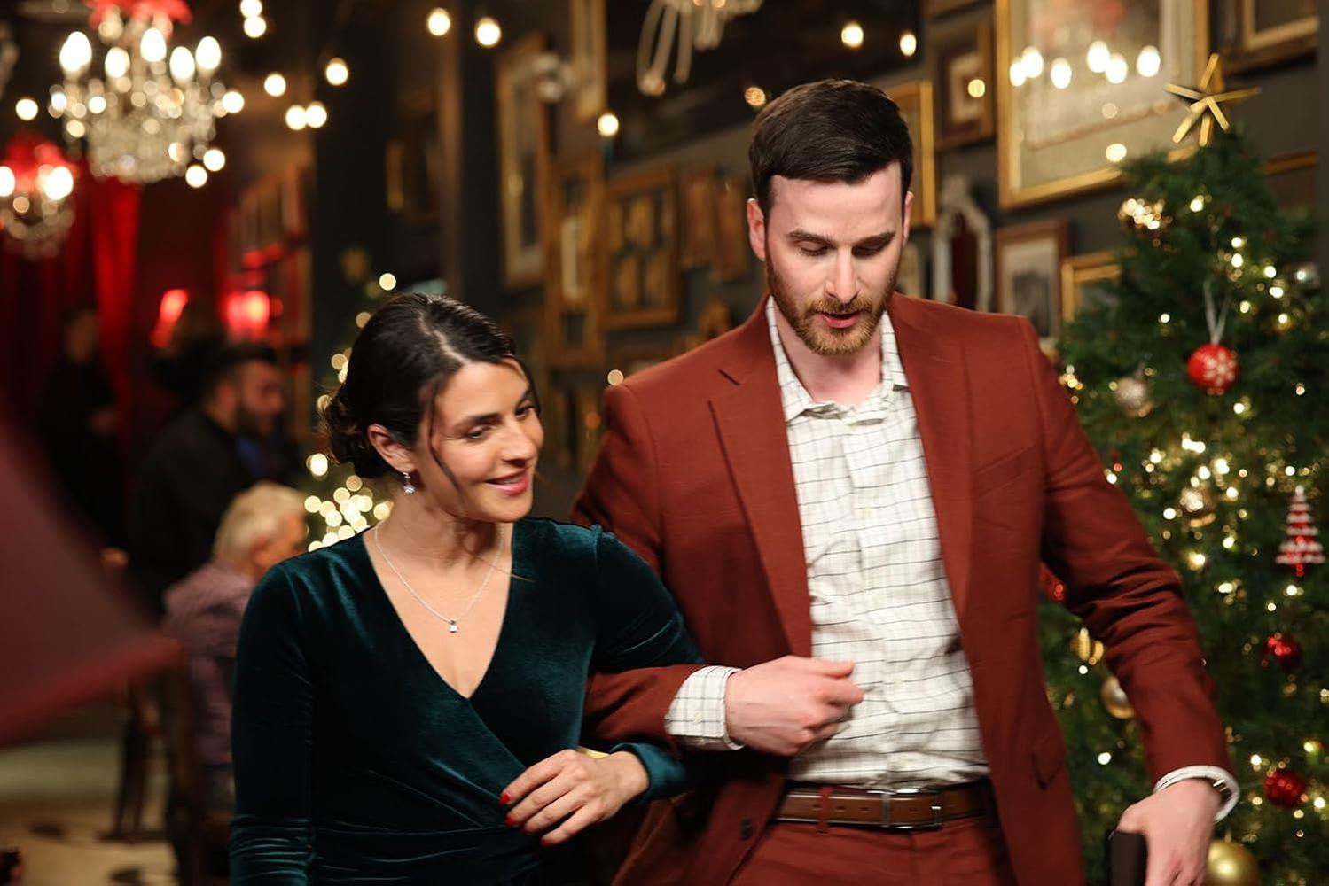 Ein Mann und eine Frau stehen zusammen in der Nähe eines Weihnachtsbaums. Der Mann trägt einen roten Anzug, die Frau ein grünes Kleid.