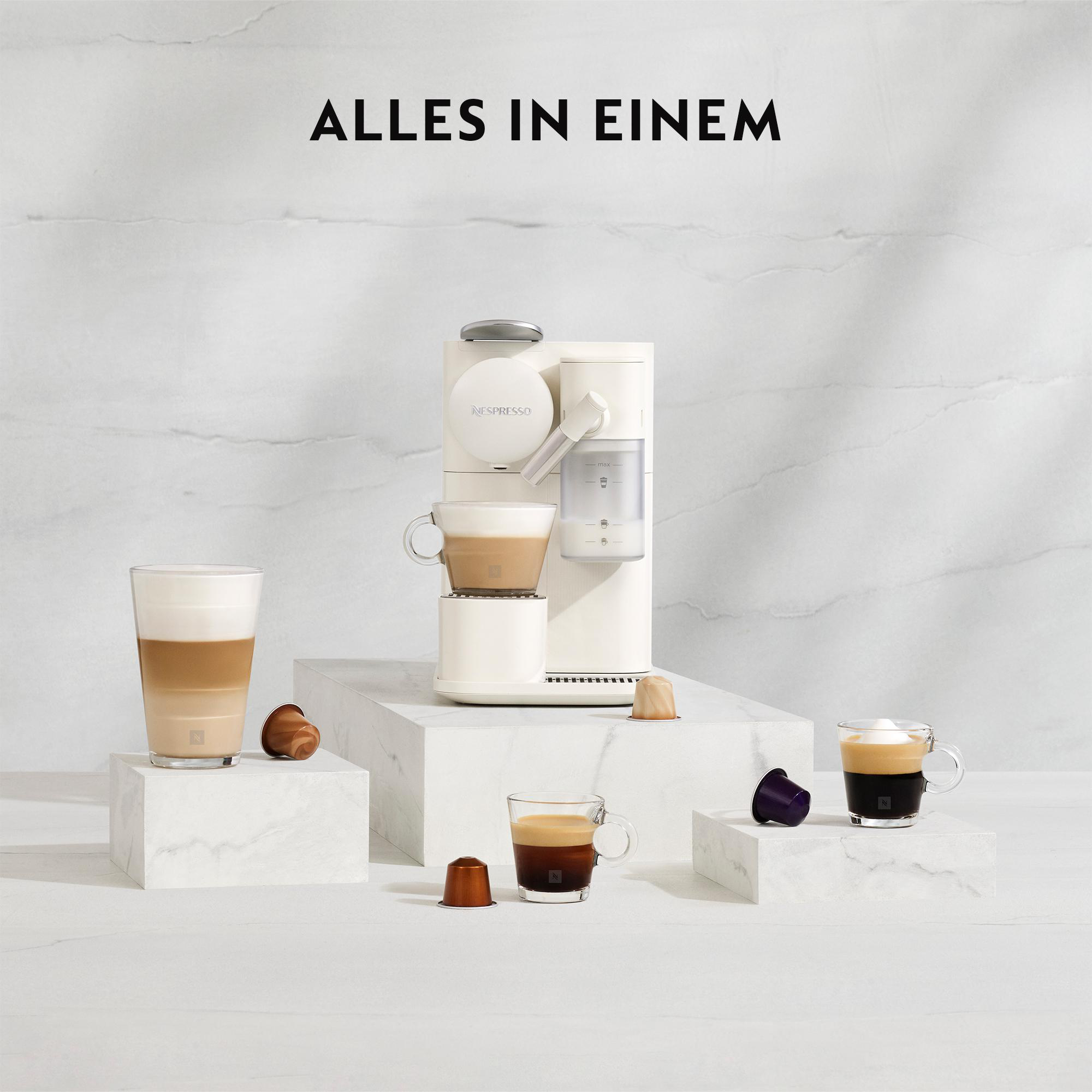 Eine Nespresso-Maschine mit Kaffeegläsern, Kapseln und einem Latte in einem klaren Glas. Der Hintergrund ist weißer Marmor.