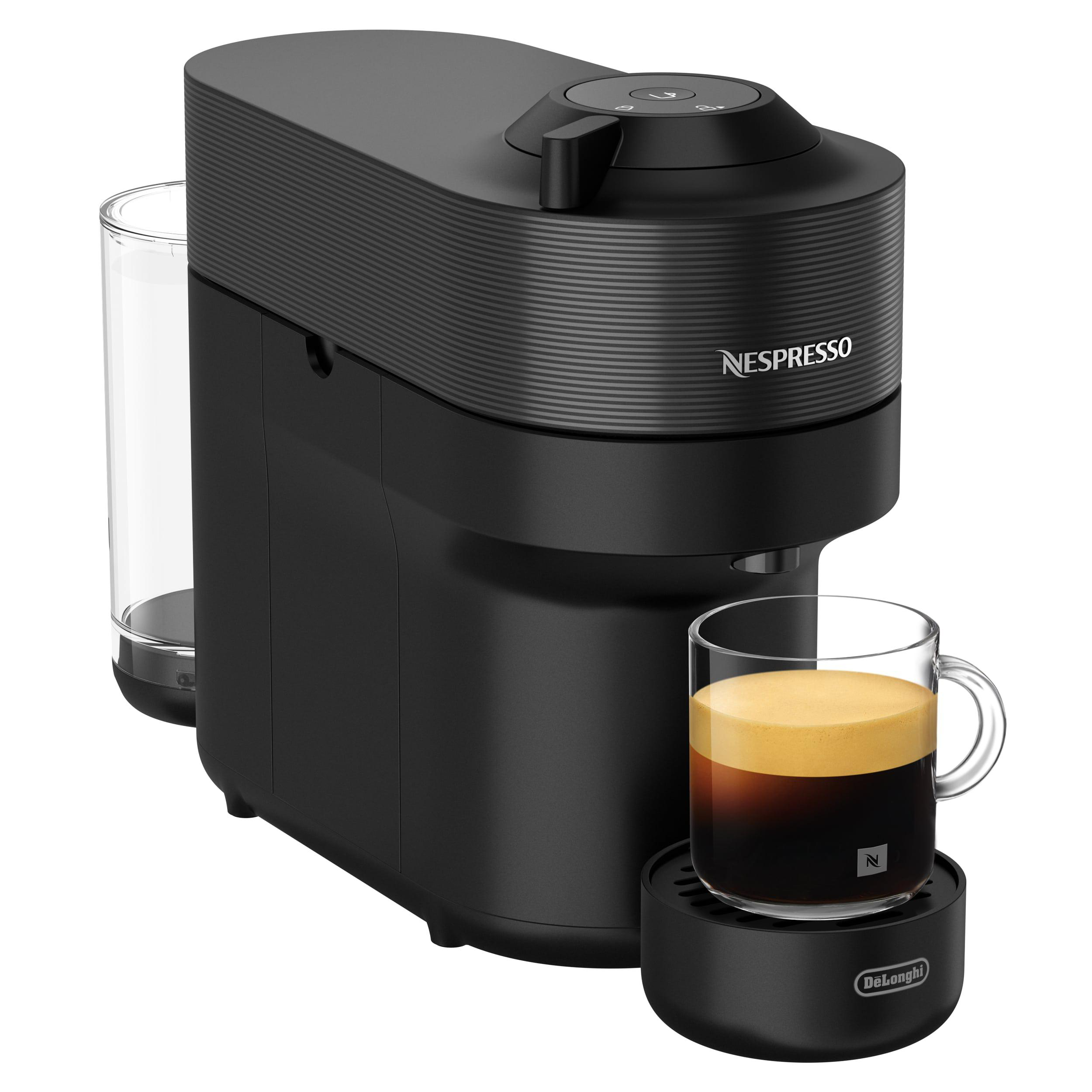 Eine schwarze Nespresso-Kaffeemaschine mit einem Glas Kaffee. Die Maschine hat links einen Wassertank.