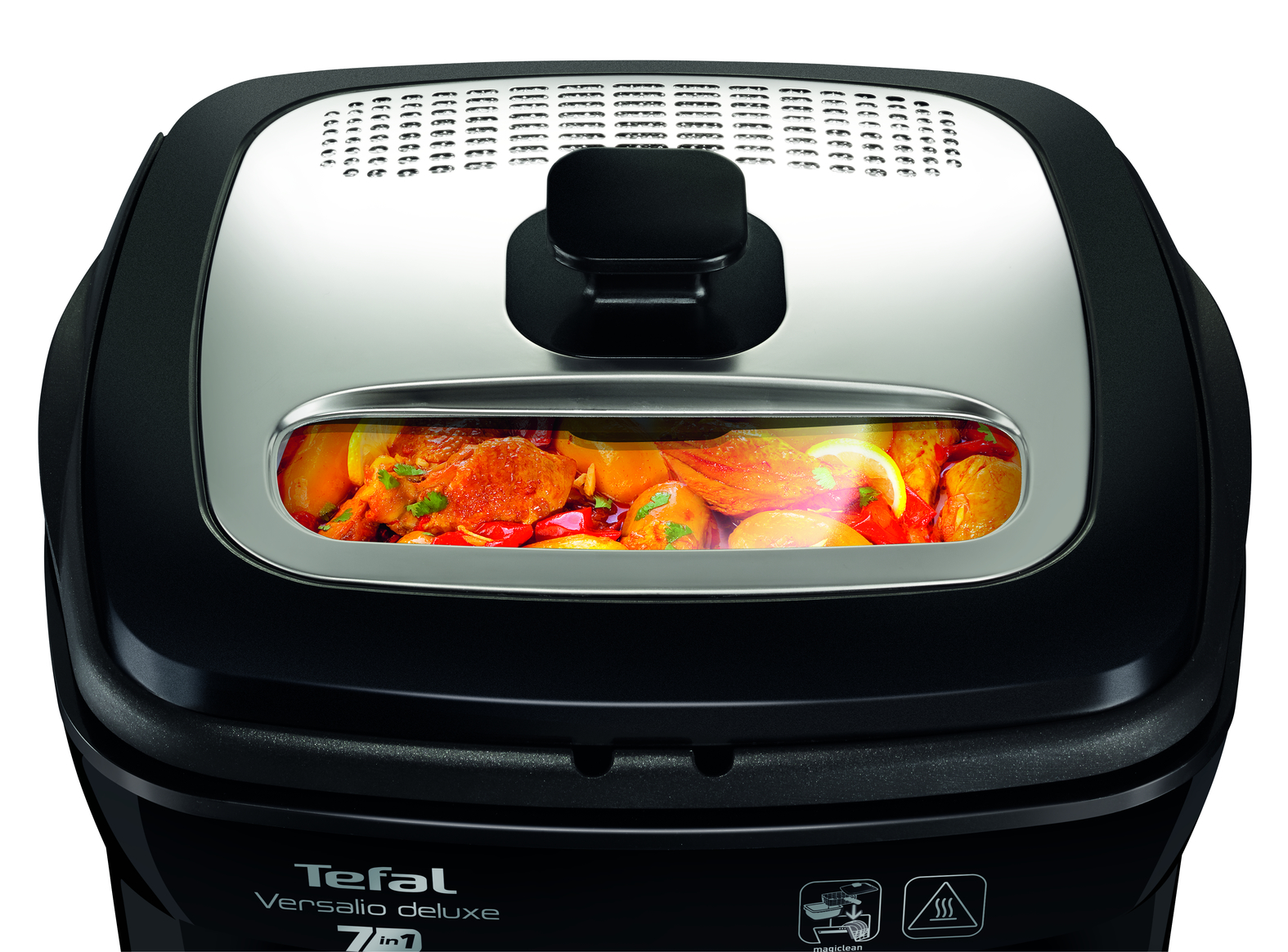 Egy fekete Tefal Versalio Deluxe 7 az 1-ben multifőzőlap átlátszó fedővel, ami főtt ételt mutat. A fedő ezüstszínű és szellőzőnyílásokkal rendelkezik.