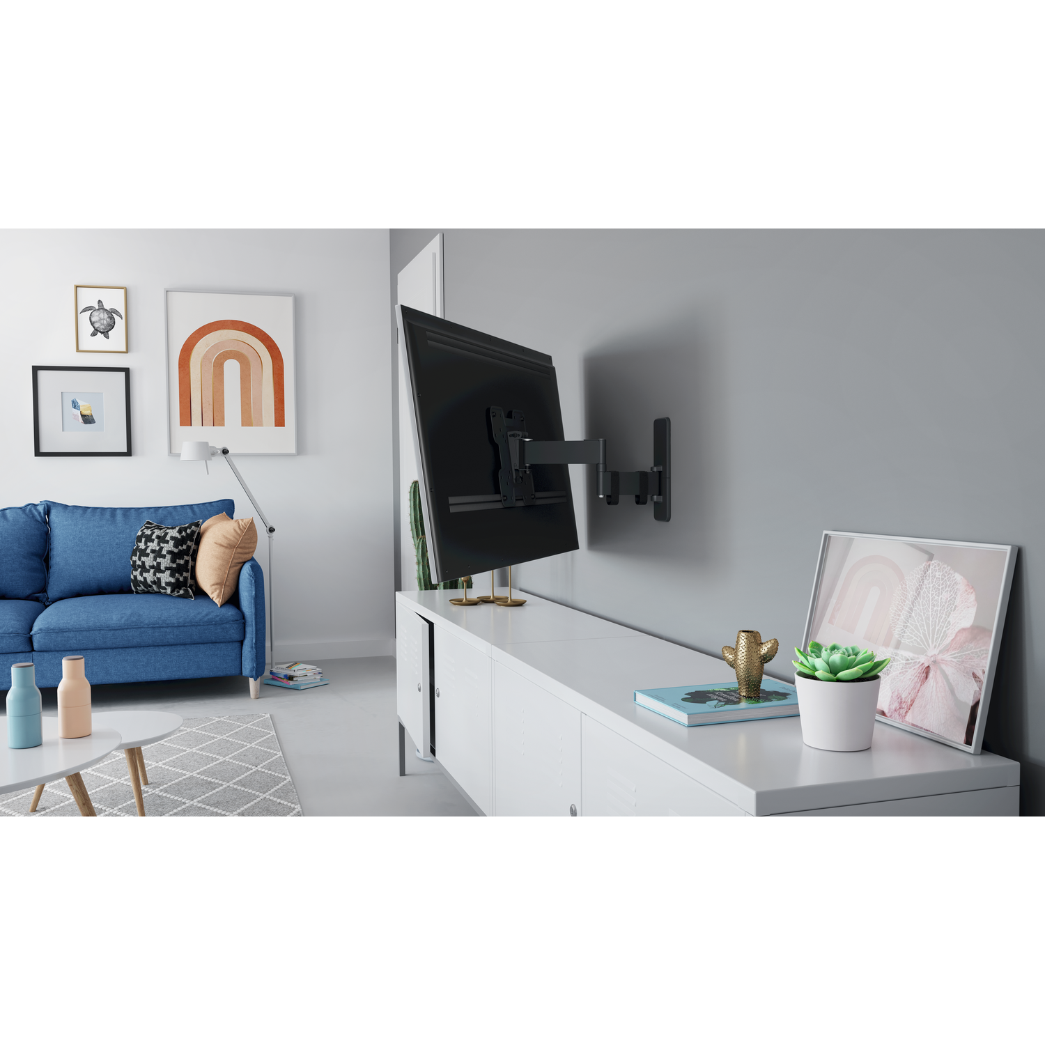 A living room with a blue sofa, white cabinet, and a TV mounted on the wall. Artwork and decor on the walls and cabinet.