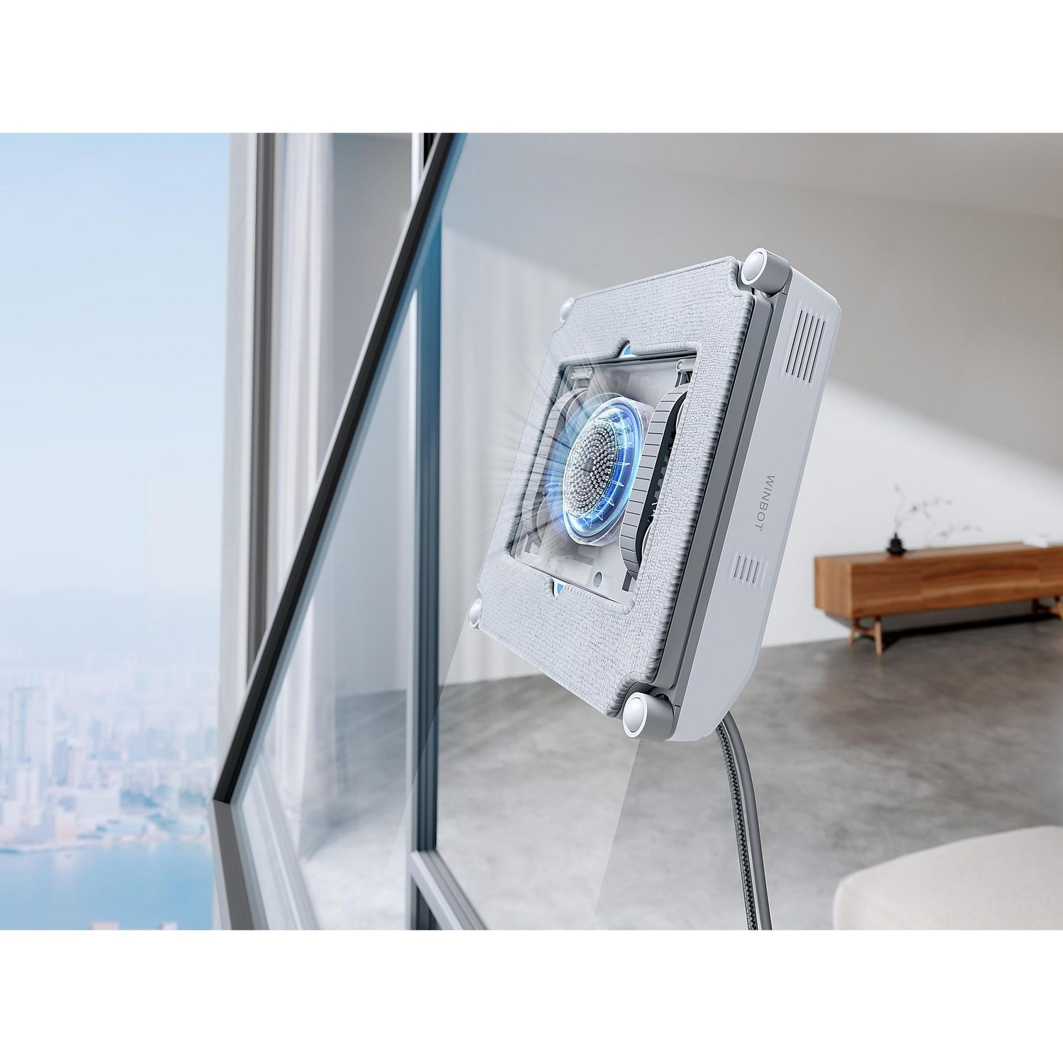 A window cleaning robot is attached to a window. The background shows a city and the sky. The robot is white and grey.