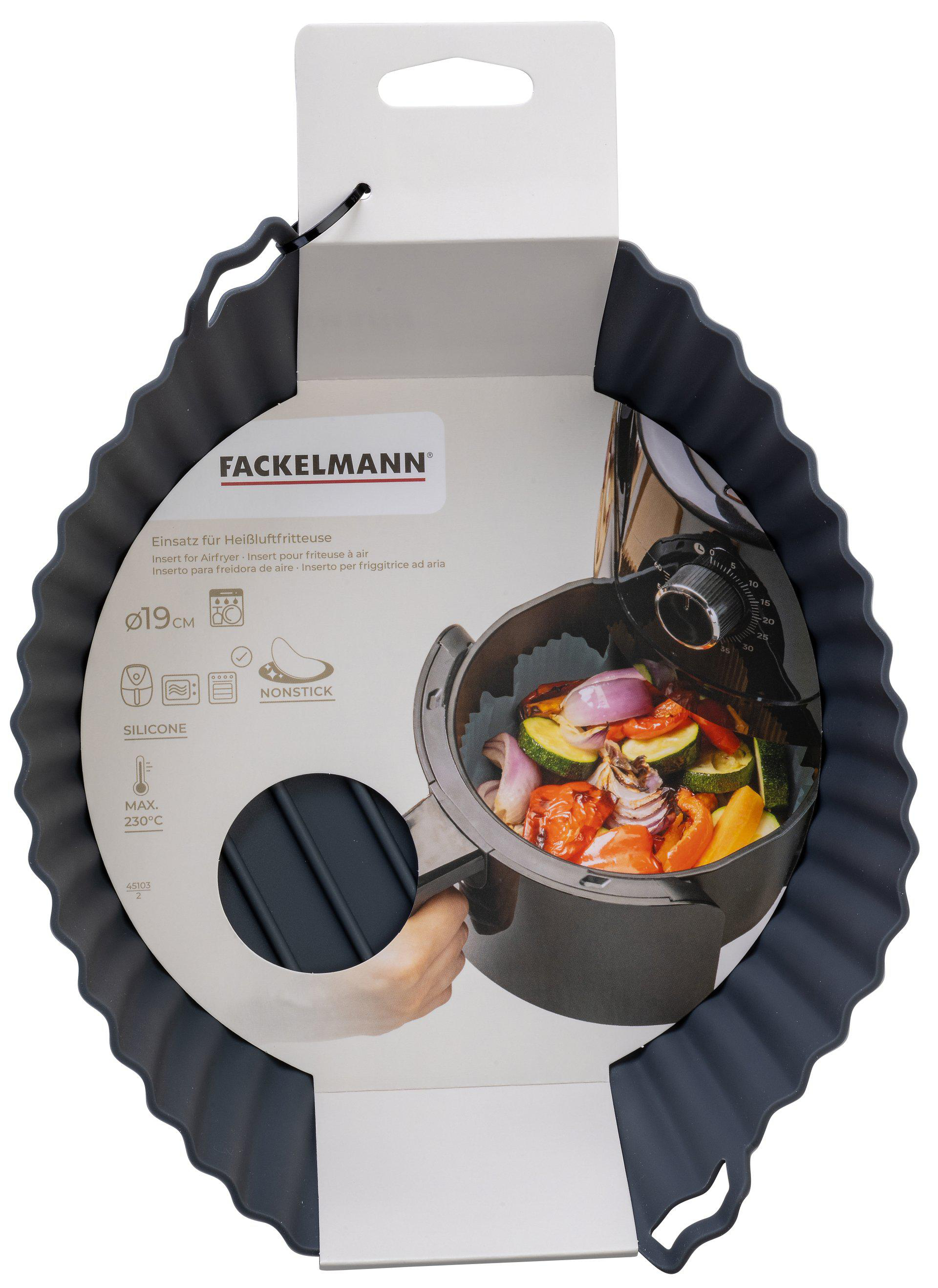 Ein Airfryer-Zubehör. Es zeigt einen schwarzen Silikoneinsatz mit einem weißen Karton und einen Airfryer mit Gemüse.