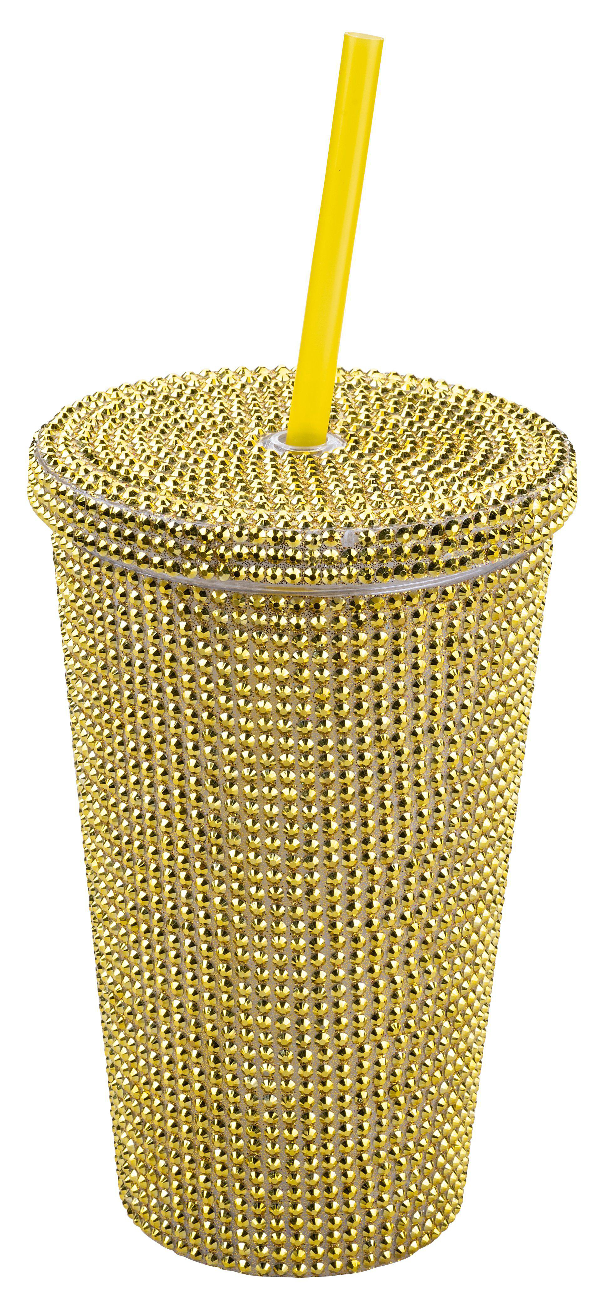 Ein mit Strasssteinen besetzter goldener Becher mit einem gelben Strohhalm. Der Becher ist mit kleinen, goldenen, glänzenden Nieten bedeckt.