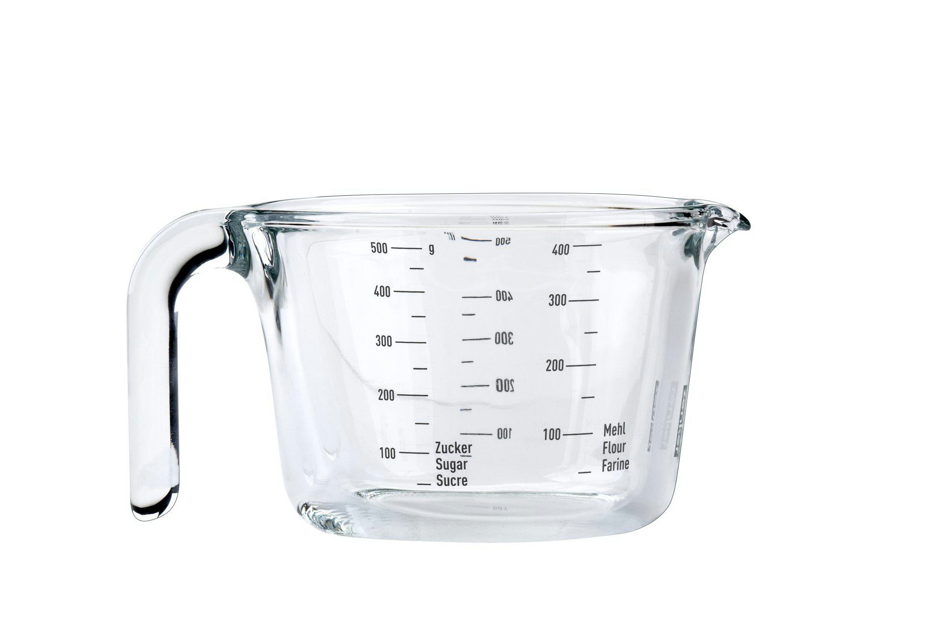Ein klarer Glasmessbecher mit Griff, abgestuften Markierungen und Etiketten für Zucker, Mehl und andere Zutaten.