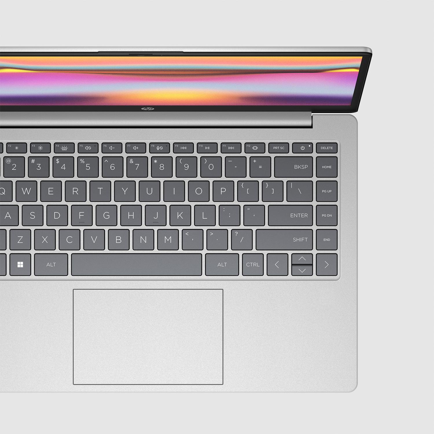 A silver laptop with a keyboard and a screen is open. The screen displays colorful abstract patterns.