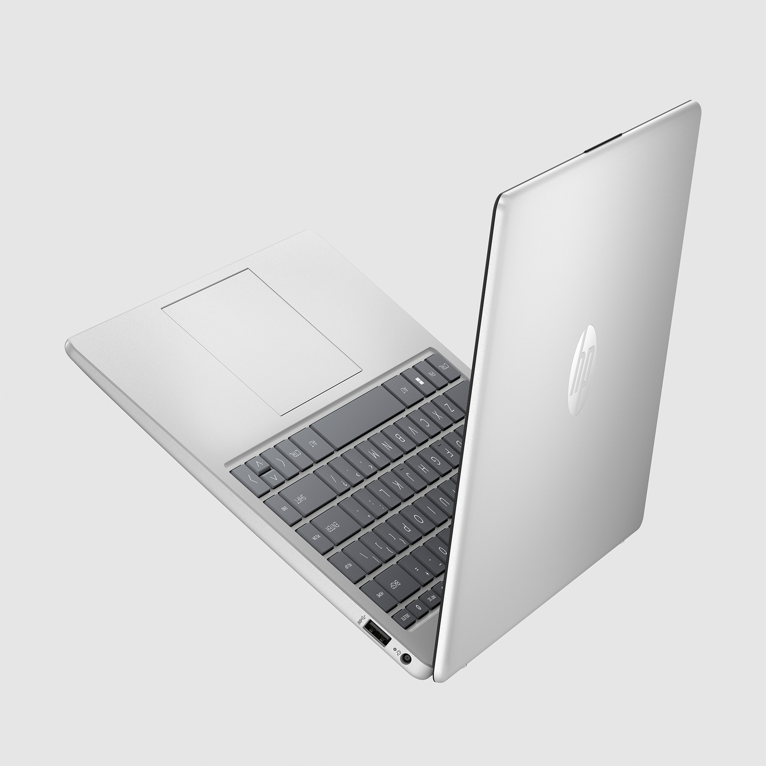 A silver laptop is open, showcasing the keyboard and trackpad. The HP logo is visible on the lid.