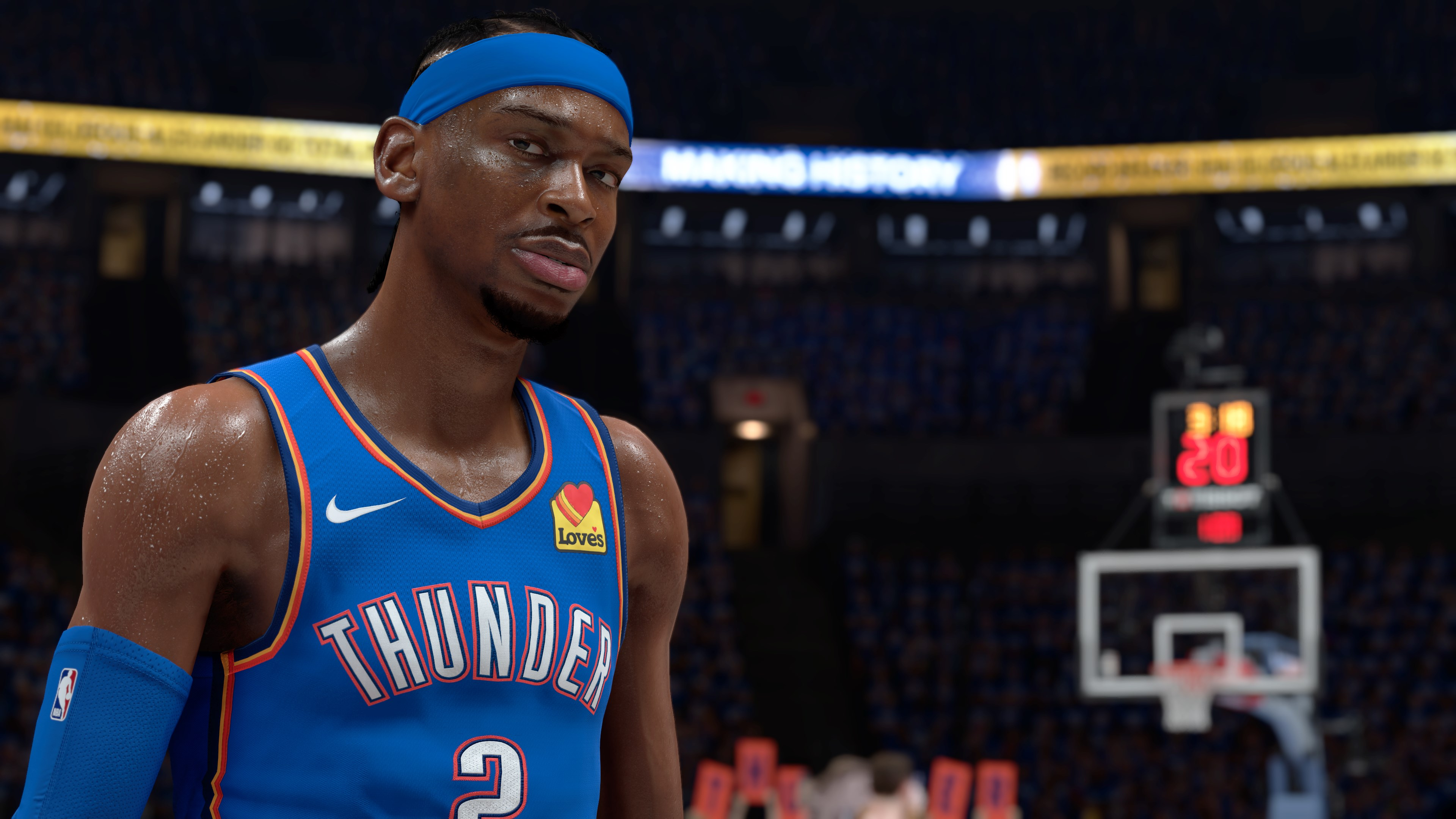 Un giocatore di basket con la maglia dei Thunder guarda la fotocamera. Il punteggio è visibile sullo sfondo. Il giocatore indossa una fascia blu.