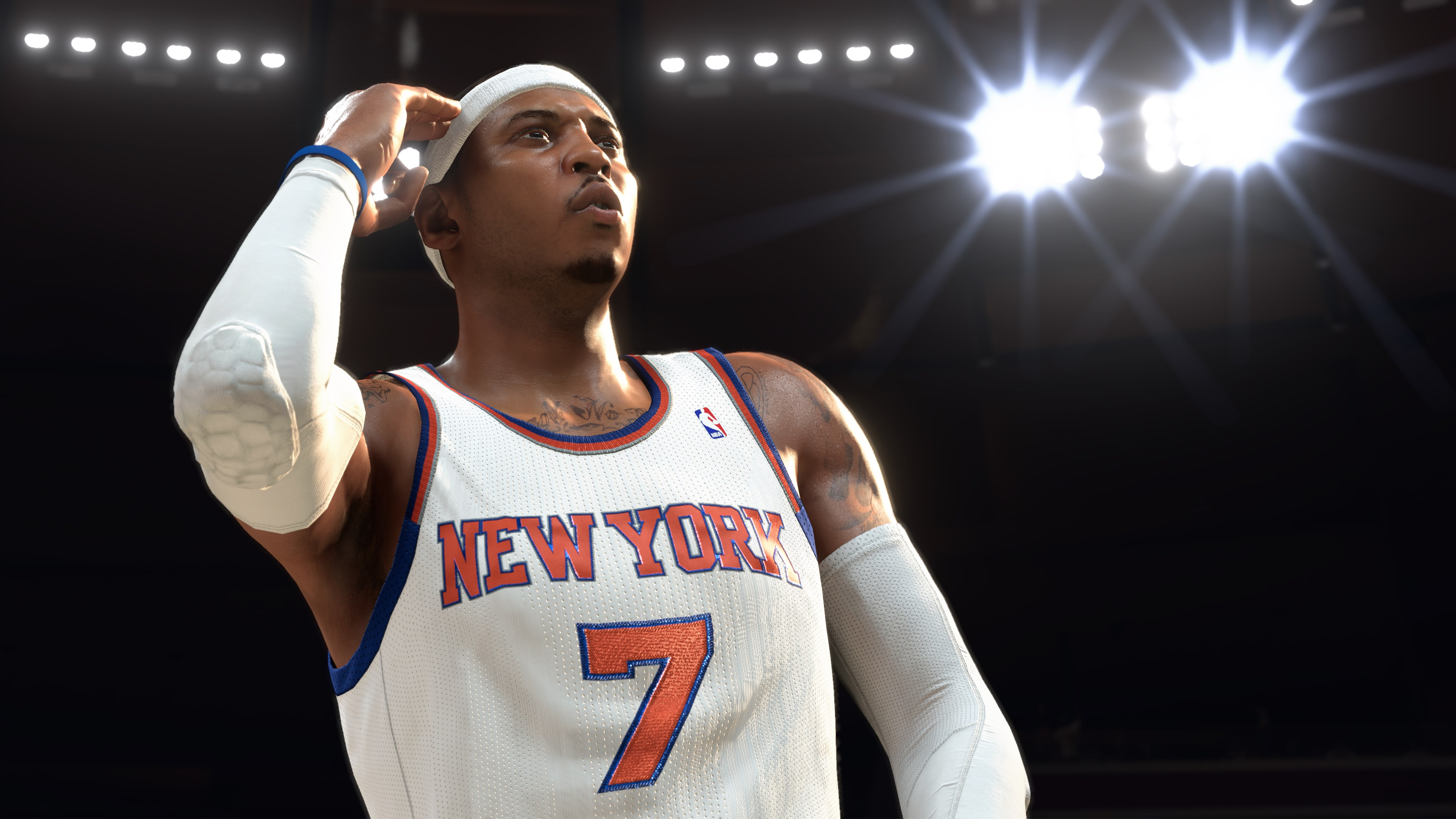 Giocatore di basket con maglia bianca con 'New York' e il numero 7. Guarda in alto, con fascia e manica.