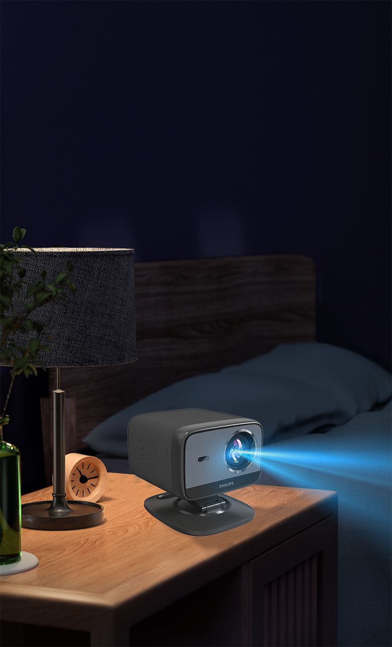 Projektor Philips na stoliku nocnym wyświetla niebieską wiązkę. Na stole znajduje się również lampa, zegar, łóżko i butelka.