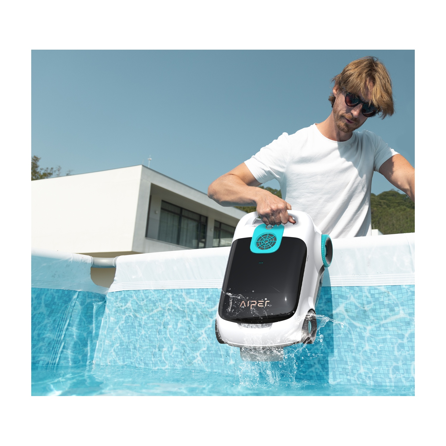 Un uomo con gli occhiali da sole mette un pulitore per piscina in una piscina. Il pulitore è bianco e nero. La piscina ha piastrelle blu.