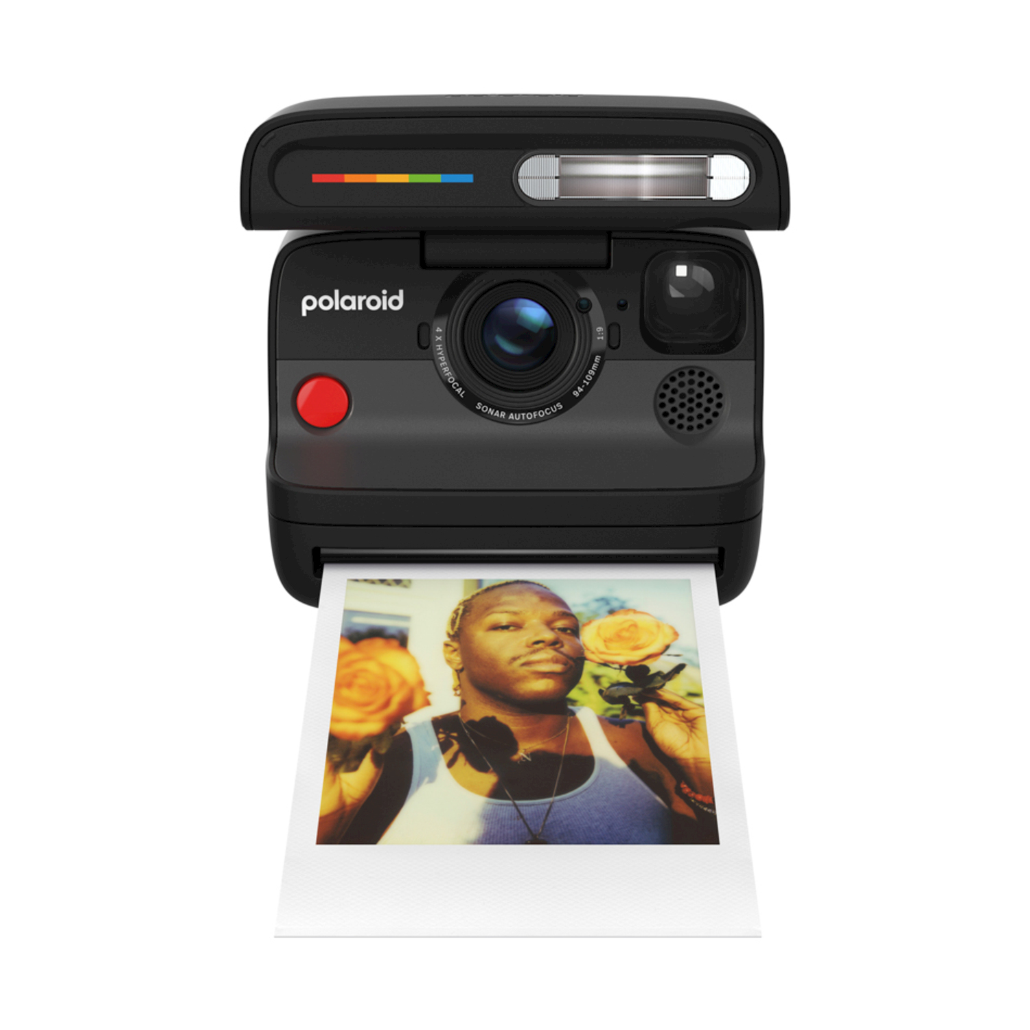 Una fotocamera Polaroid nera con una foto che esce. La foto mostra una persona che tiene delle rose. Lo sfondo è bianco.