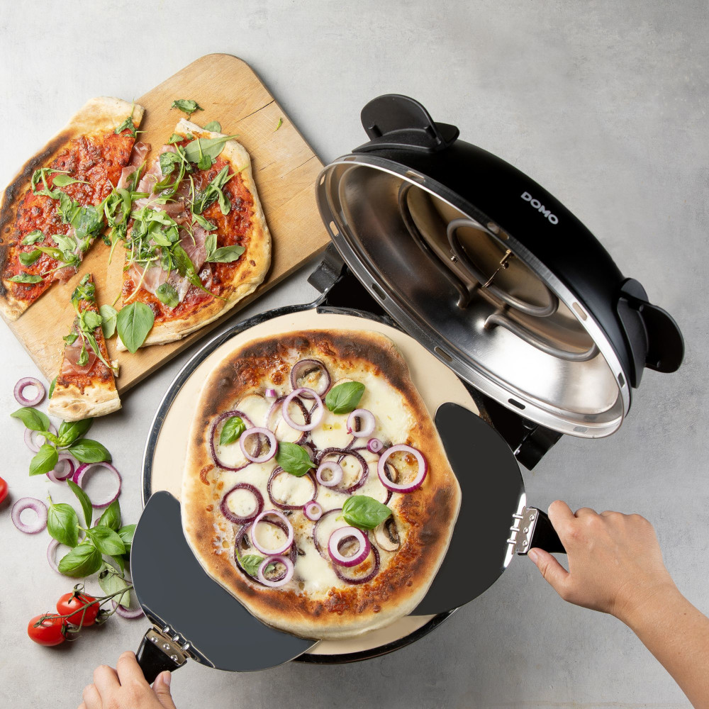 A pizza oven with two pizzas, one with toppings, and one with mozzarella and onions. Pizza is on a stone base.
