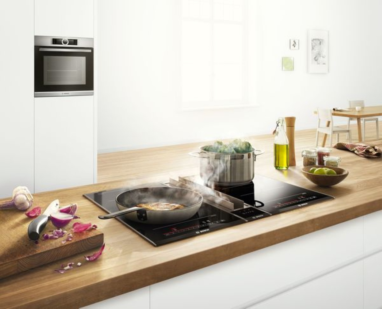 Nowoczesna kuchnia z kuchenką, gotującym się jedzeniem, deską do krojenia i piekarnikiem. W tle stół i krzesła.