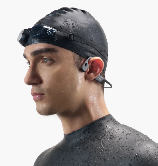 Mann mit Schwimmkappe und Brille, trägt ein Headset. Er ist nass, wahrscheinlich vom Schwimmen. Isoliert auf weißem Hintergrund.