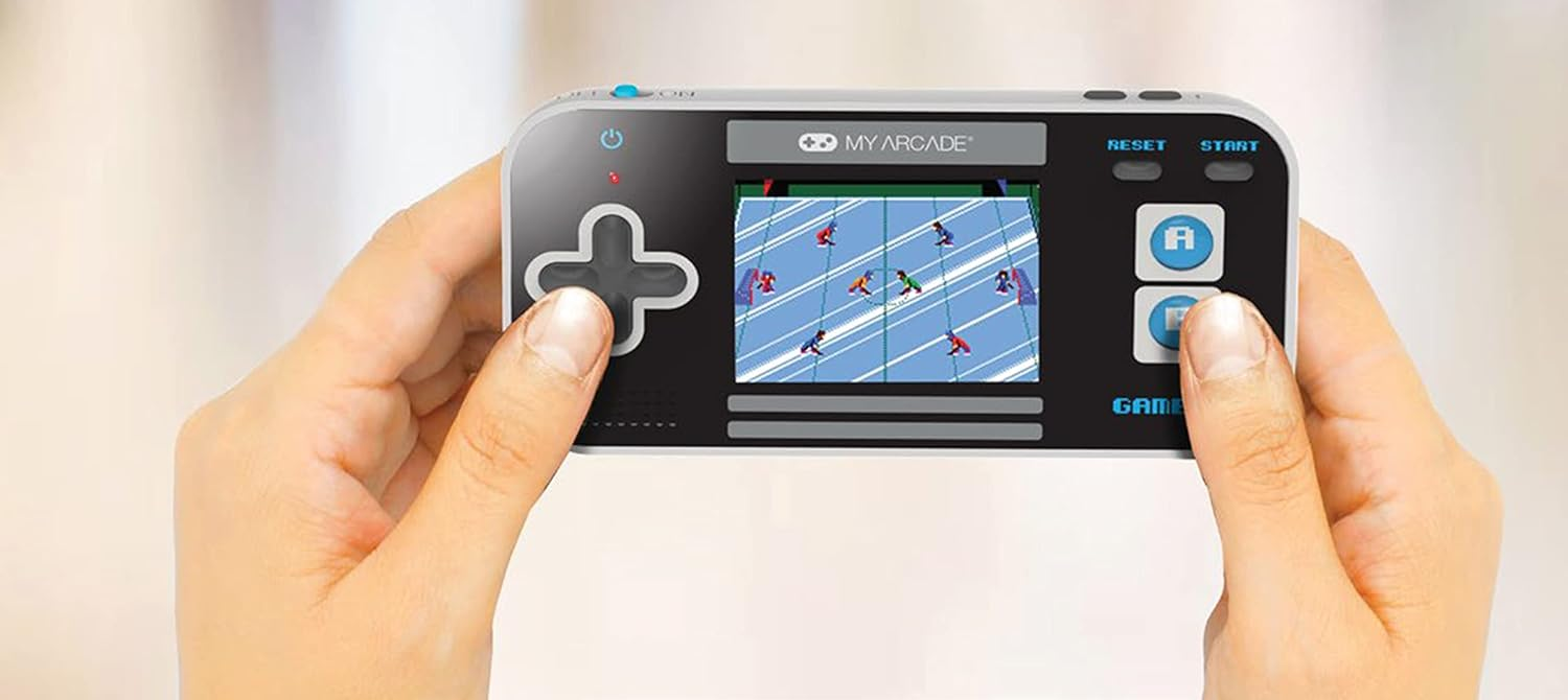 Mains tenant une console de jeu portable. L'écran affiche un match de football. Boutons et une croix directionnelle sont visibles.