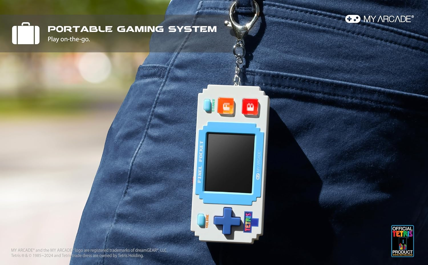 Un système de jeu portable, Pixel Pocket, est suspendu à un porte-clés. Il est accroché à une poche de jean bleu. Le système de jeu a un écran et le logo Tetris.