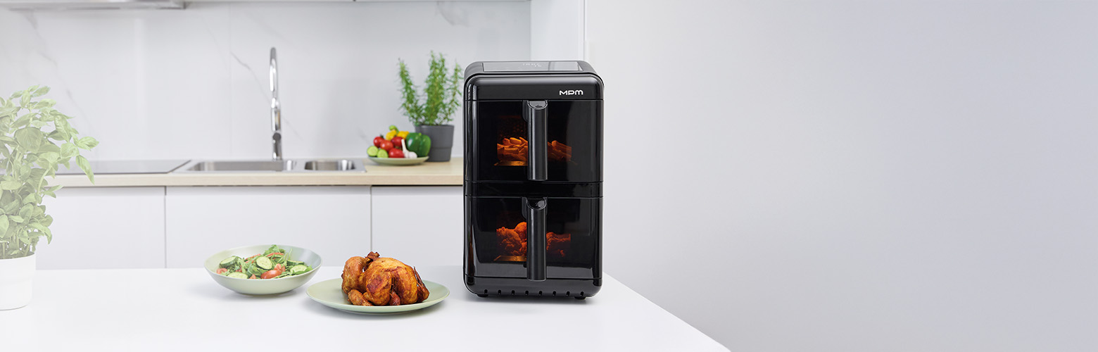 Czarna frytkownica powietrzna z jedzeniem, pieczony kurczak i sałatka na białym stole. Tło kuchni.