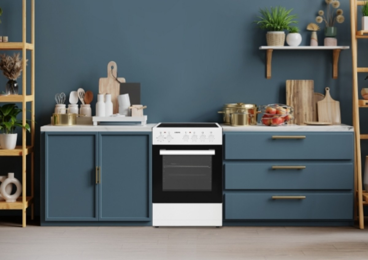 Wnętrze kuchni z niebieskimi szafkami, białym piekarnikiem, półkami z roślinami oraz różnymi przyborami kuchennymi i dekoracjami.