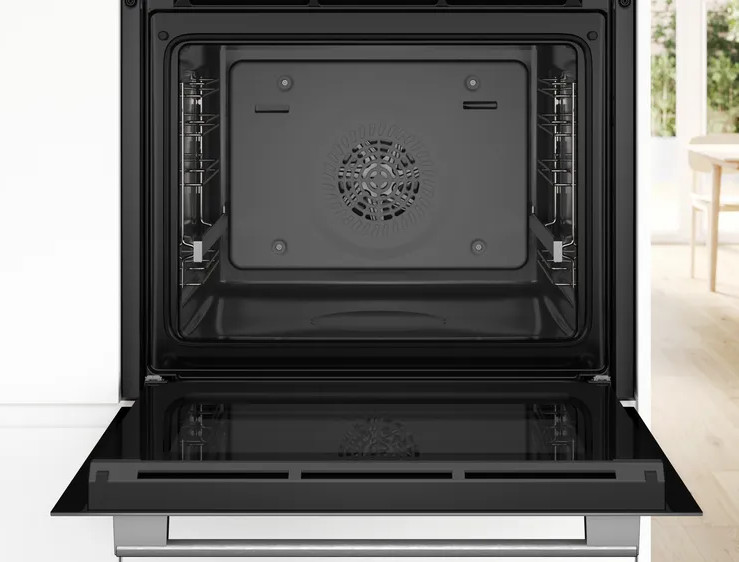 Otwarty wnętrze piekarnika, czarne. W środku znajdują się ruszty i wentylator. Drzwi są otwarte, odbijając pokój.
