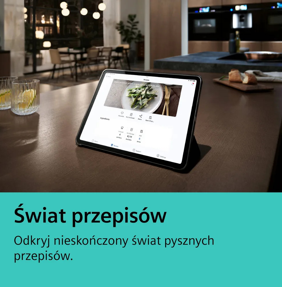 Tablet na blacie z przepisem. Przód: szklanki z napojami. Tło: kuchnia i jadalnia, jedzenie na drewnianej desce.