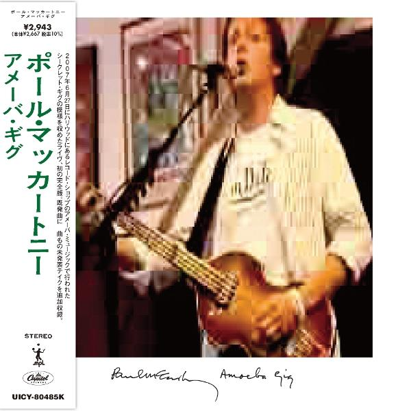 Paul McCartney spielt Bassgitarre auf der Bühne. Er singt in ein Mikrofon. Albumcover mit japanischem Text und Unterschrift.