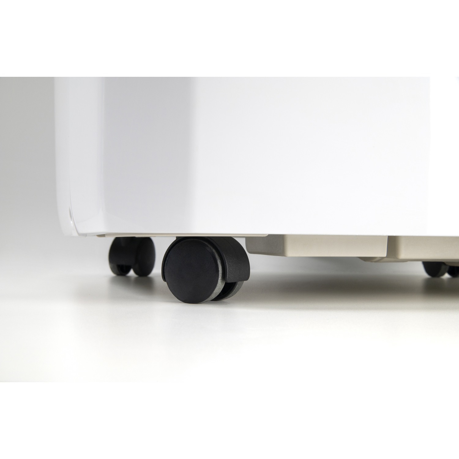 Close-up of the bottom of a white appliance with black wheels on a white surface. The wheels are visible.