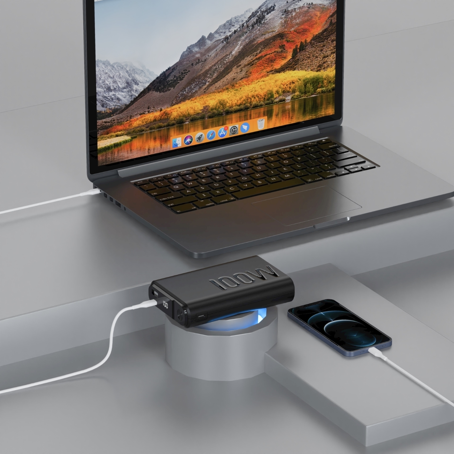 Un laptop, un telefono e un power bank sono collegati con cavi bianchi. Il laptop mostra una vista montana. Il power bank è nero.