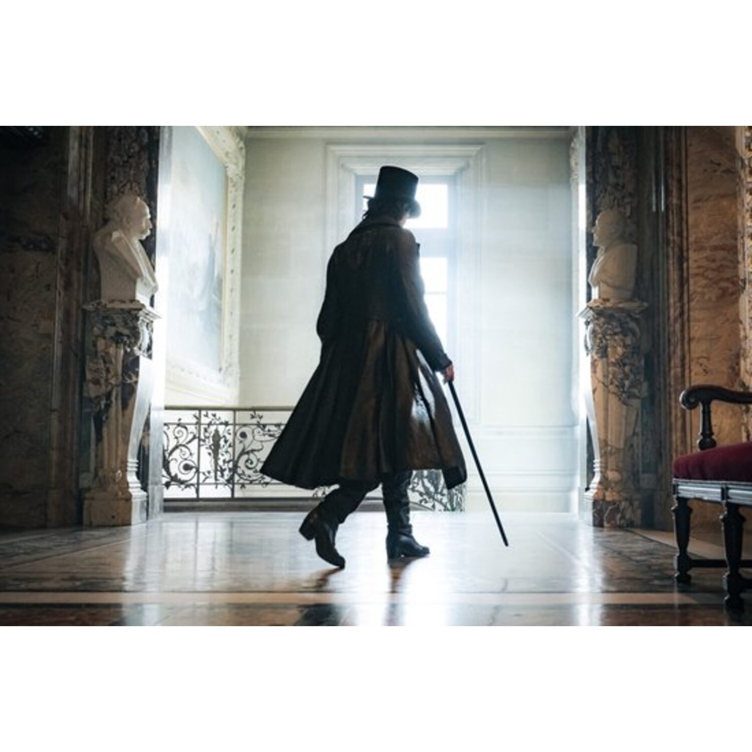 Un homme en long manteau et haut-de-forme marche dans un couloir, tenant une canne. Des statues et une peinture sont visibles.
