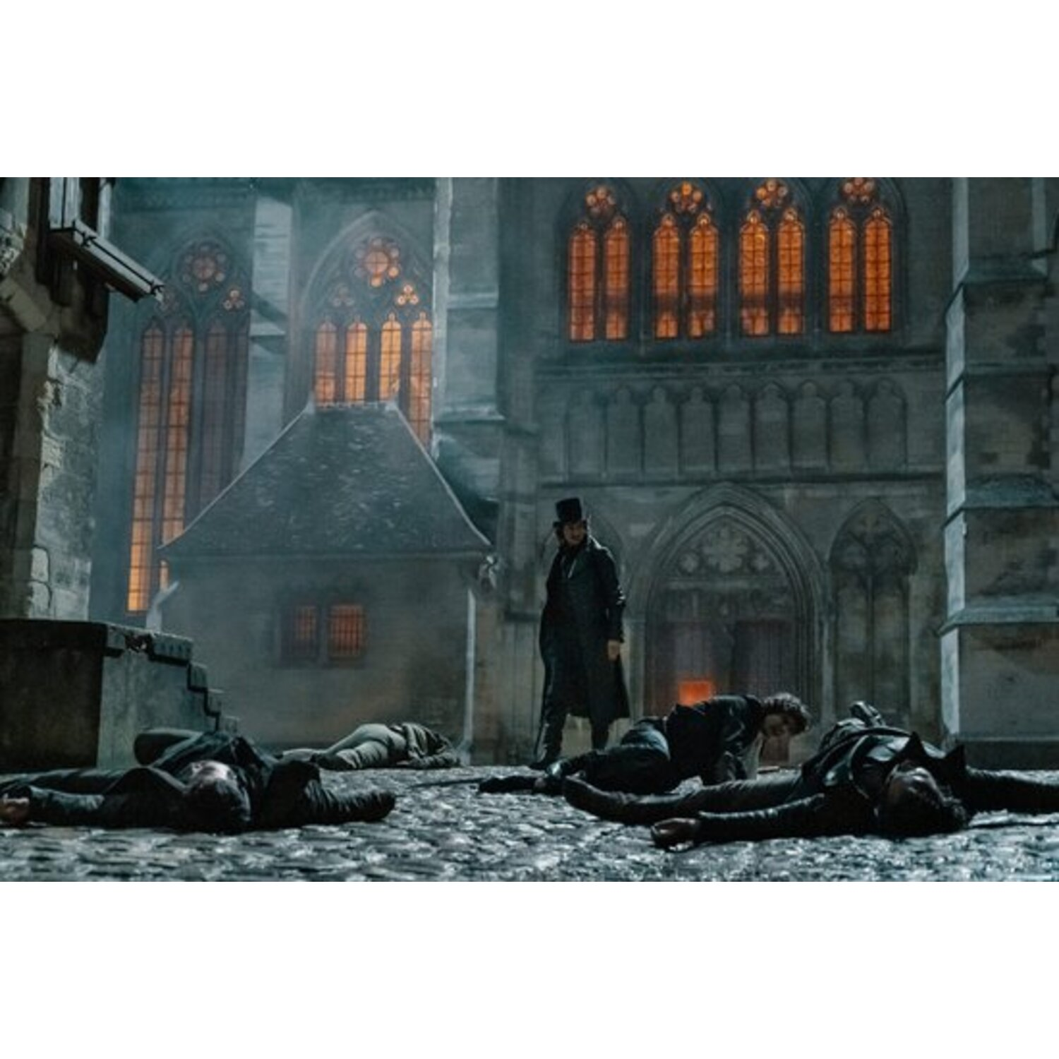 A man in a top hat stands over several fallen figures. A gothic building with stained glass windows forms the backdrop.