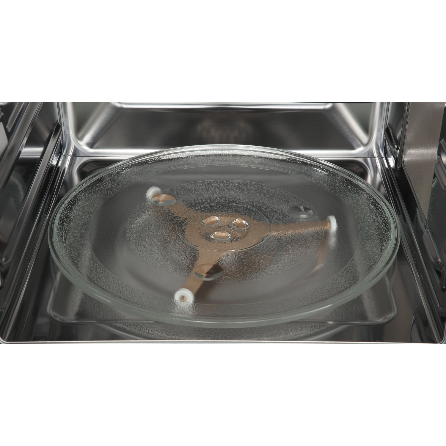 Inside a microwave oven: A glass plate sits on a rotating base. Stainless steel interior reflects light.