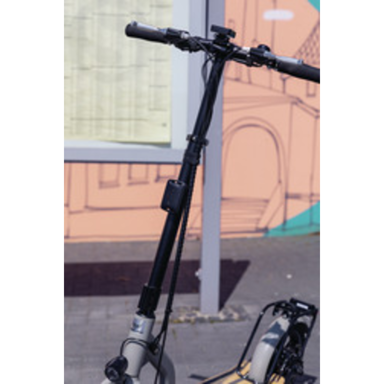 Black and grey scooter, parked outside. The handlebars are visible with a light-colored body. Background has building with arches and a window.