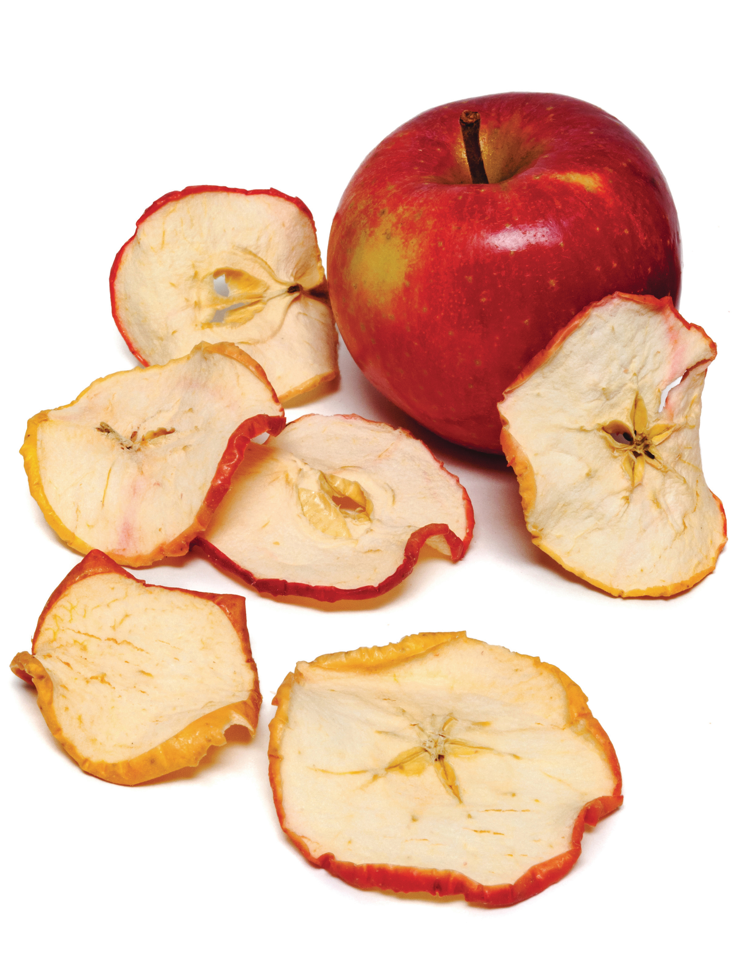 Ein ganzer roter Apfel und getrocknete Apfelscheiben auf weißem Untergrund.
