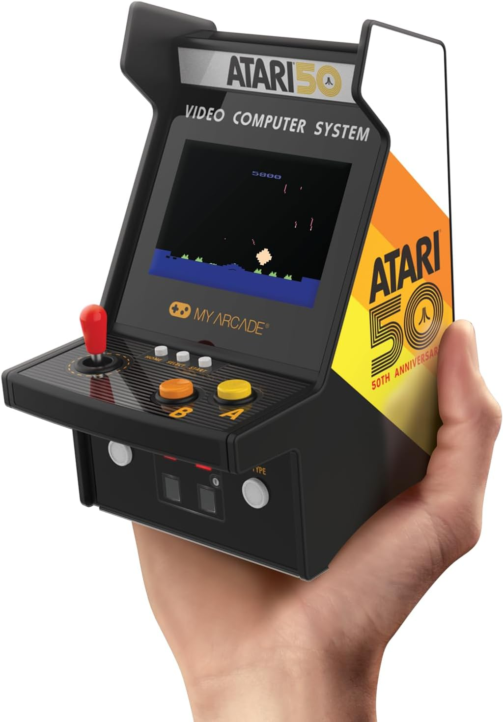 Une personne tient une petite borne d'arcade Atari. L'écran affiche une scène de jeu. Il est noir avec des formes blanches et possède un joystick rouge.
