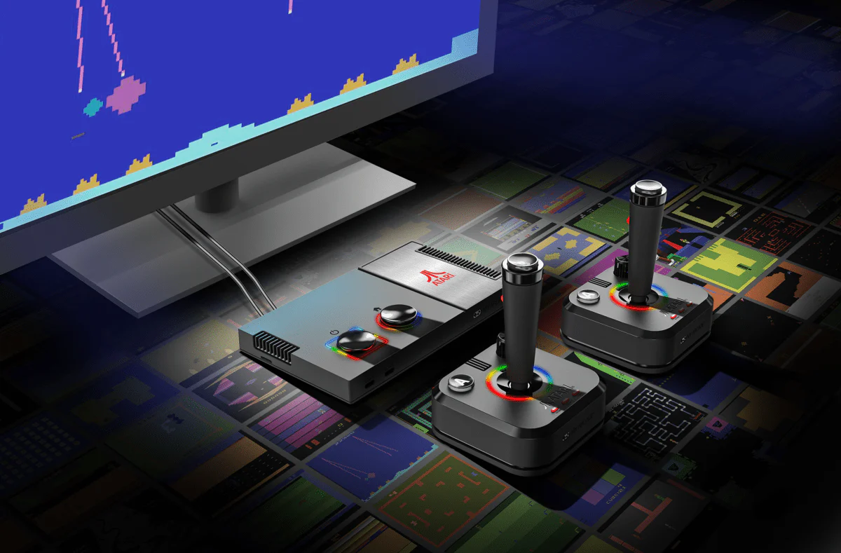 Une console Atari avec deux manettes de jeu est posée sur un fond coloré d'images de jeux pixélisées. Un moniteur affiche un jeu classique.