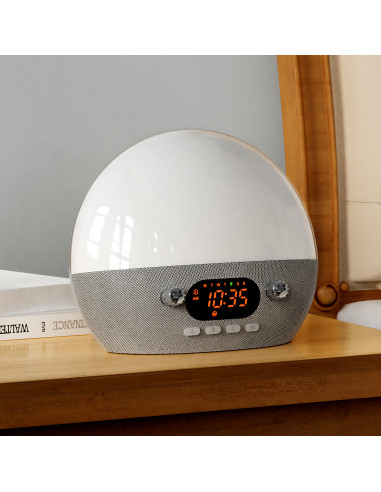 Un despertador blanco y gris muestra las 10:35. Está sobre una mesita de noche de madera con un libro y una pared gris clara al fondo.