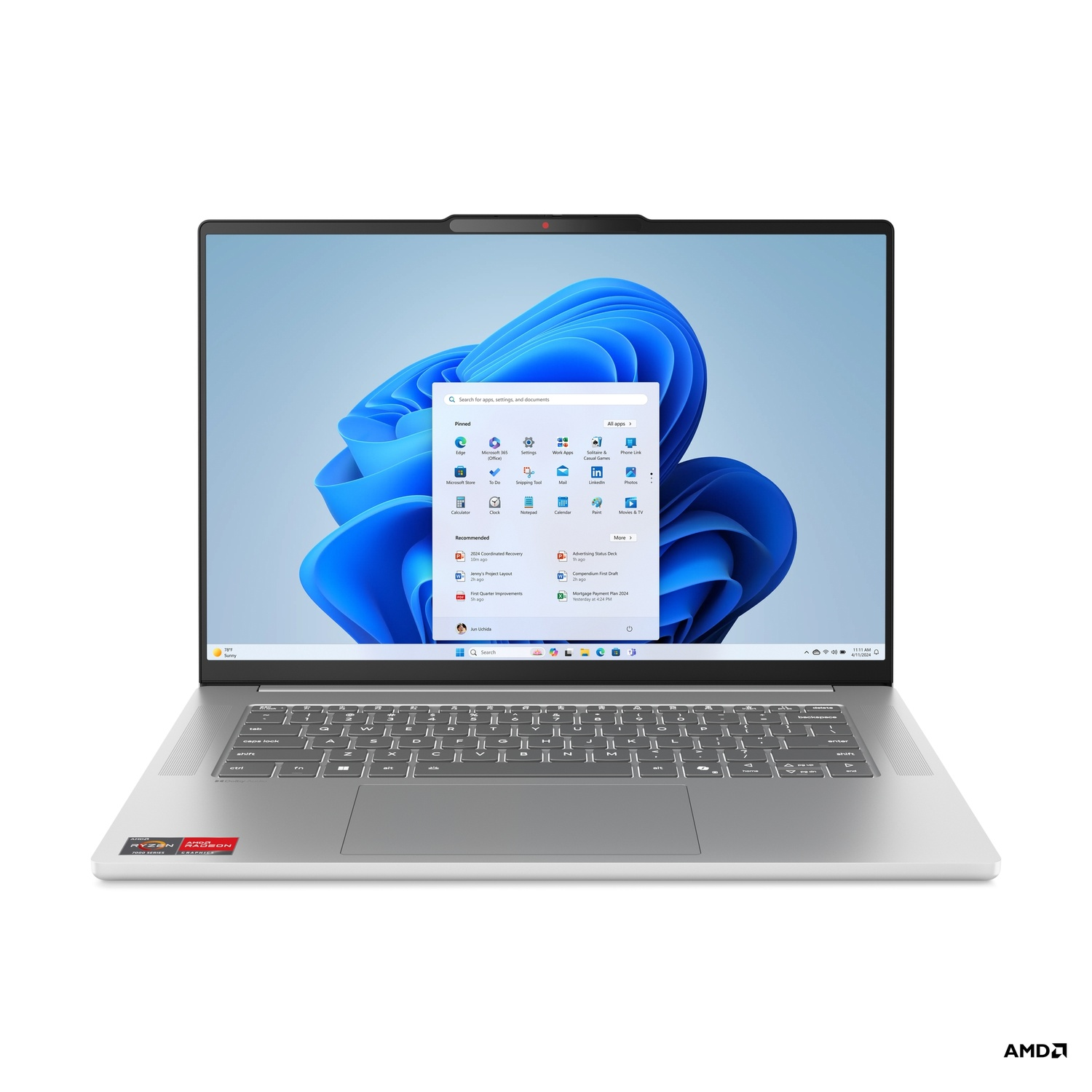 A silver laptop displaying the Windows 11 interface. The screen shows the start menu with various app icons and a search bar. The AMD logo is visible.